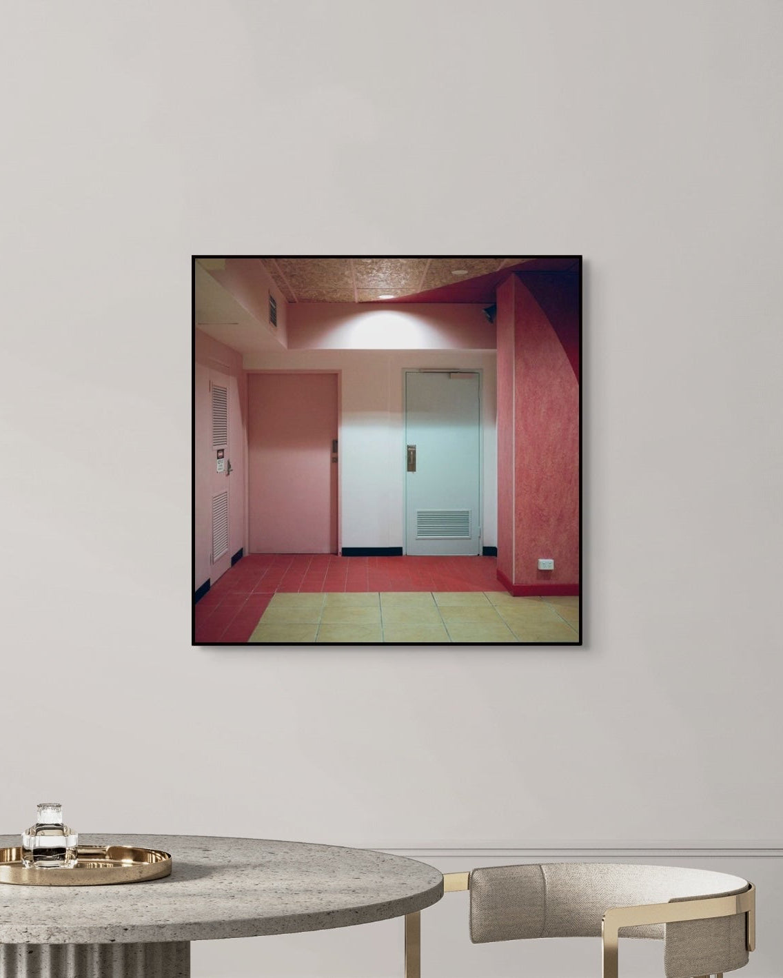 Framed photograph of a room with red walls and a door, hanging on a white wall above a table.