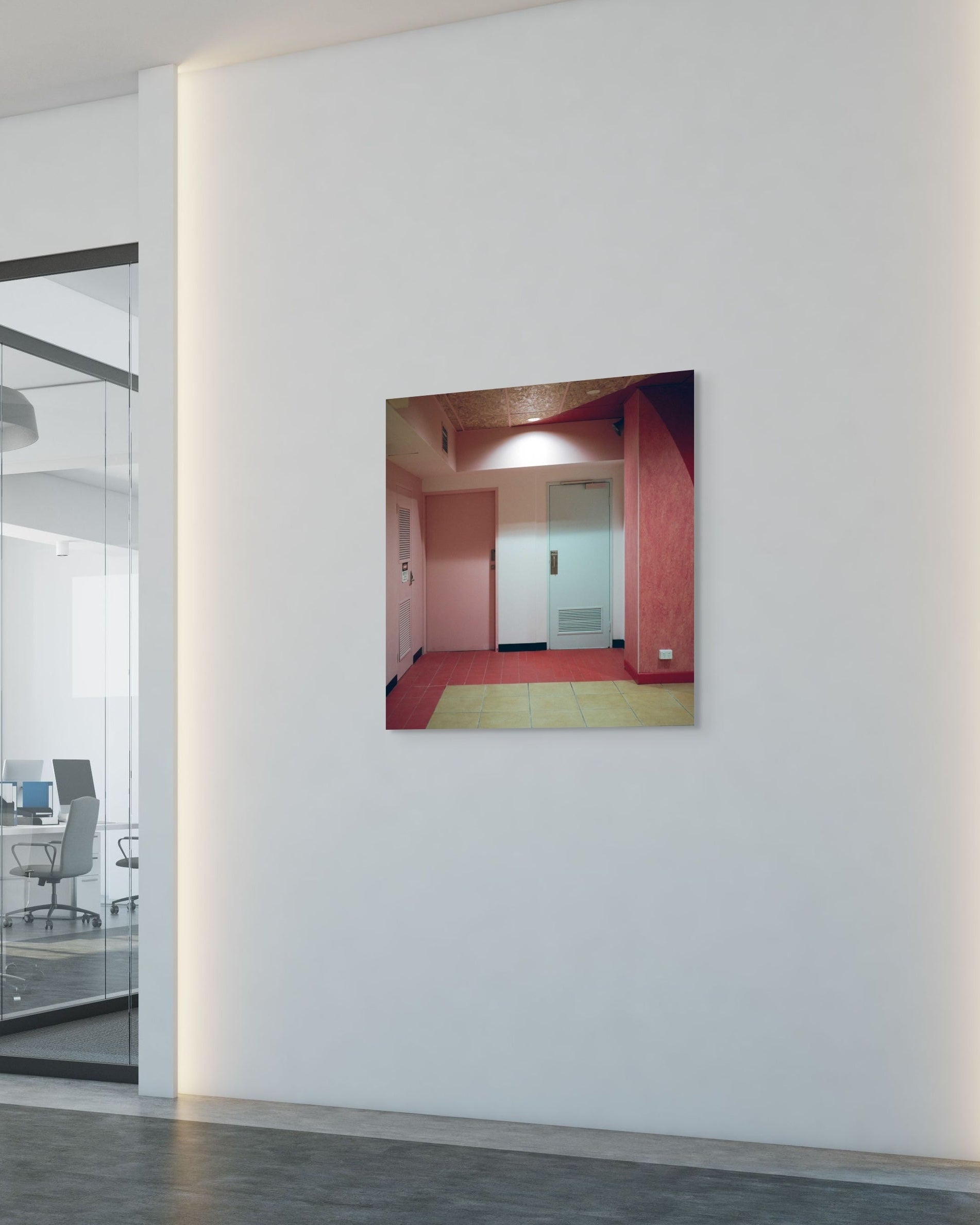 Square metal print on a white wall reflecting an office interior.