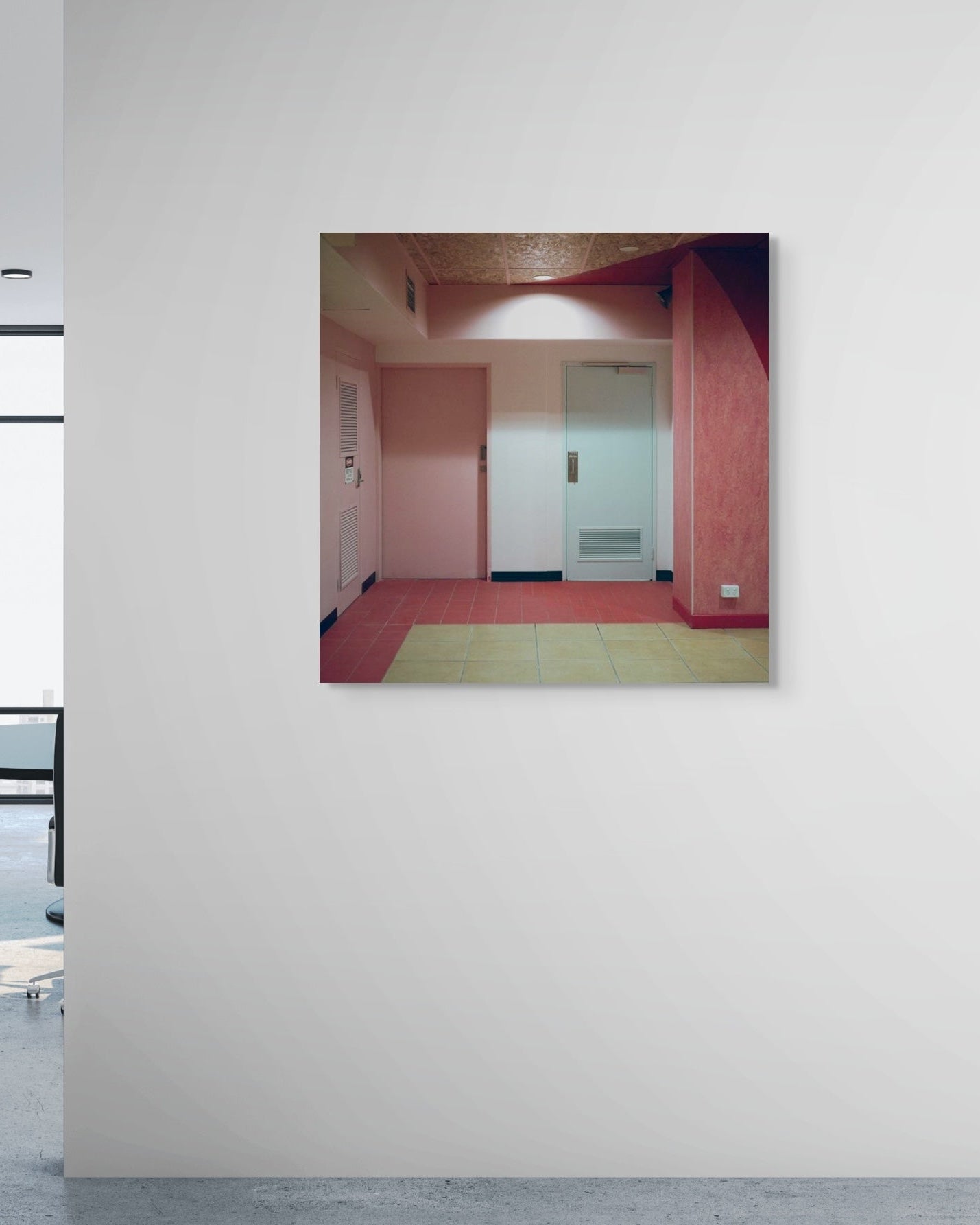 Framed photograph of a room with pink walls and a green rug on a white wall.