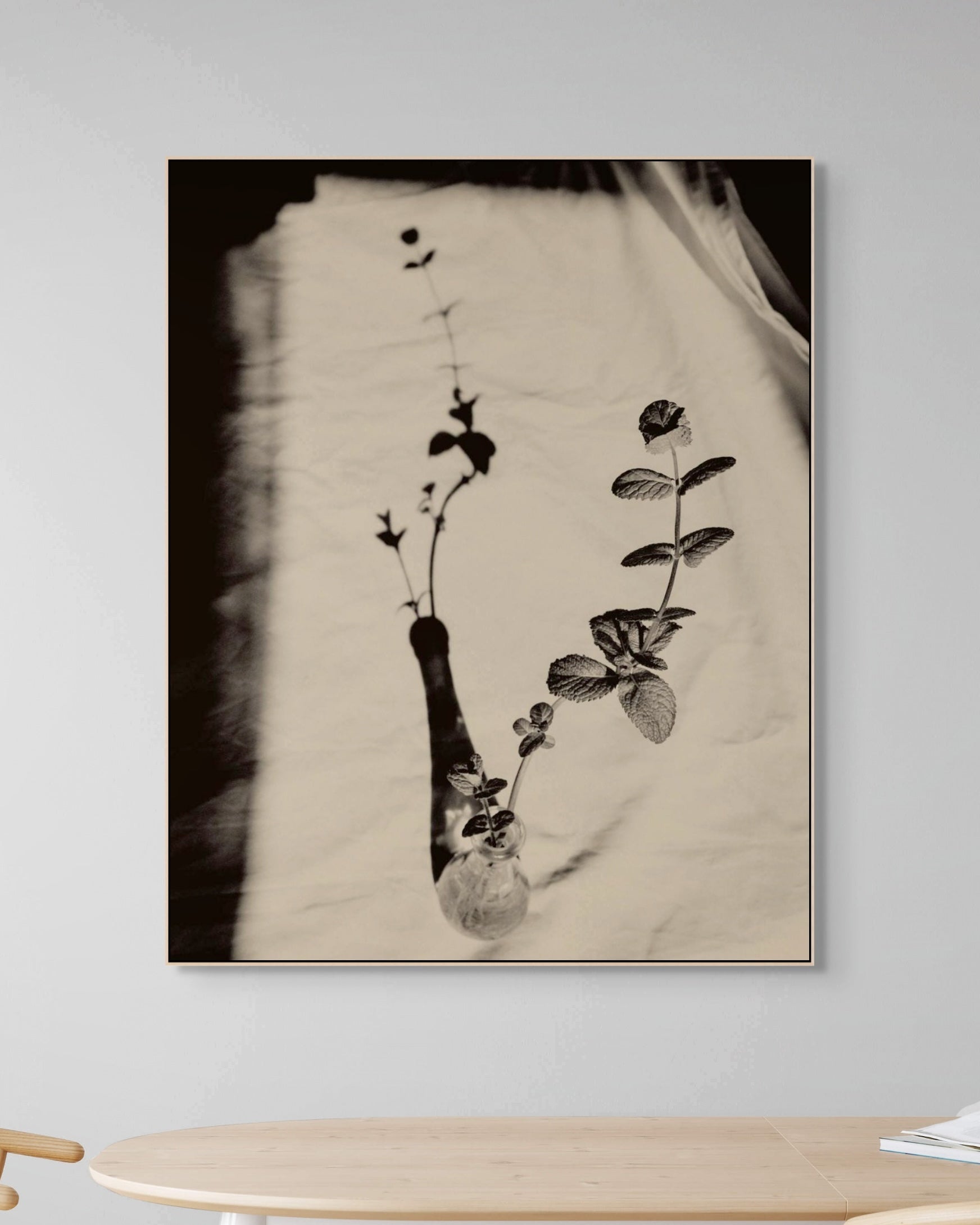Framed artwork of a minimalist black and white floral design on a wall above a wooden table.