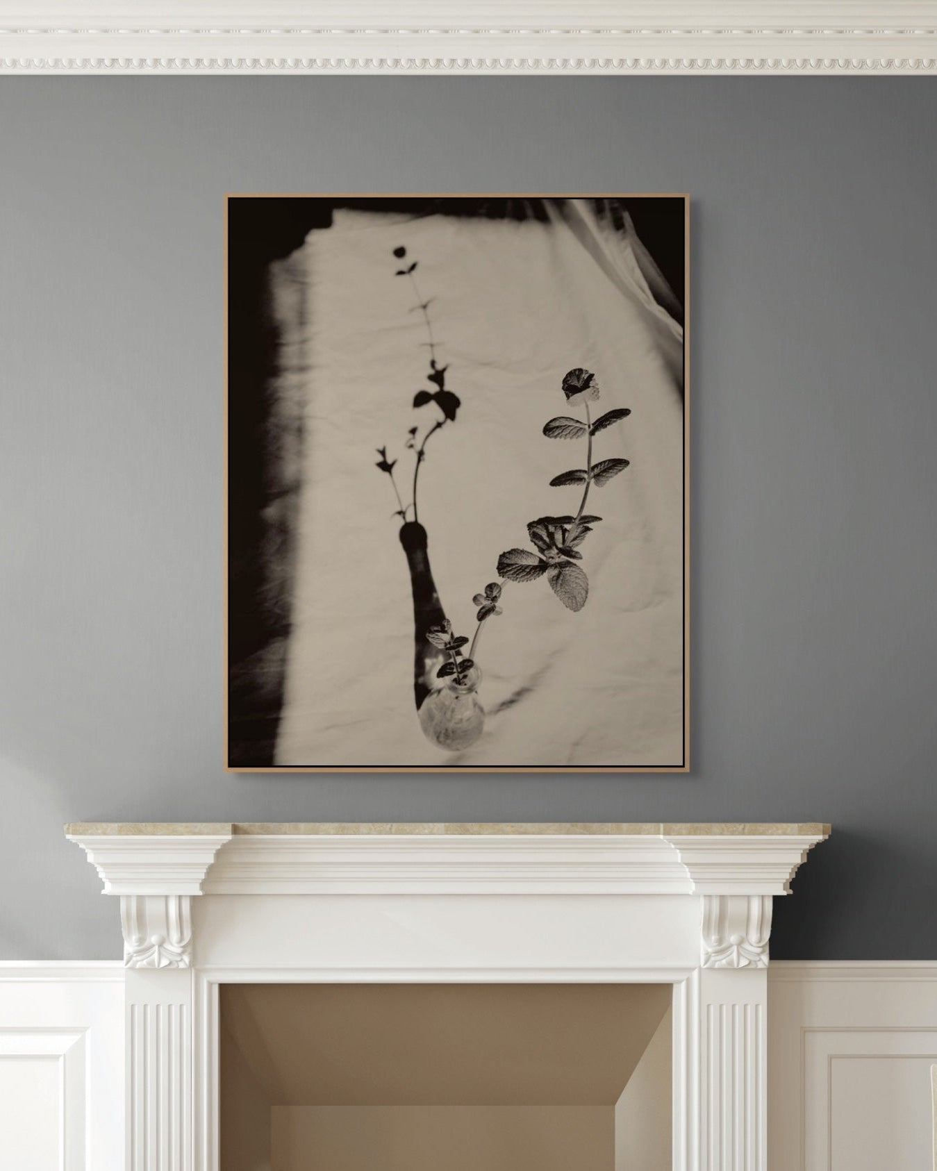 Framed artwork of a plant on a gray wall above a white fireplace mantle.