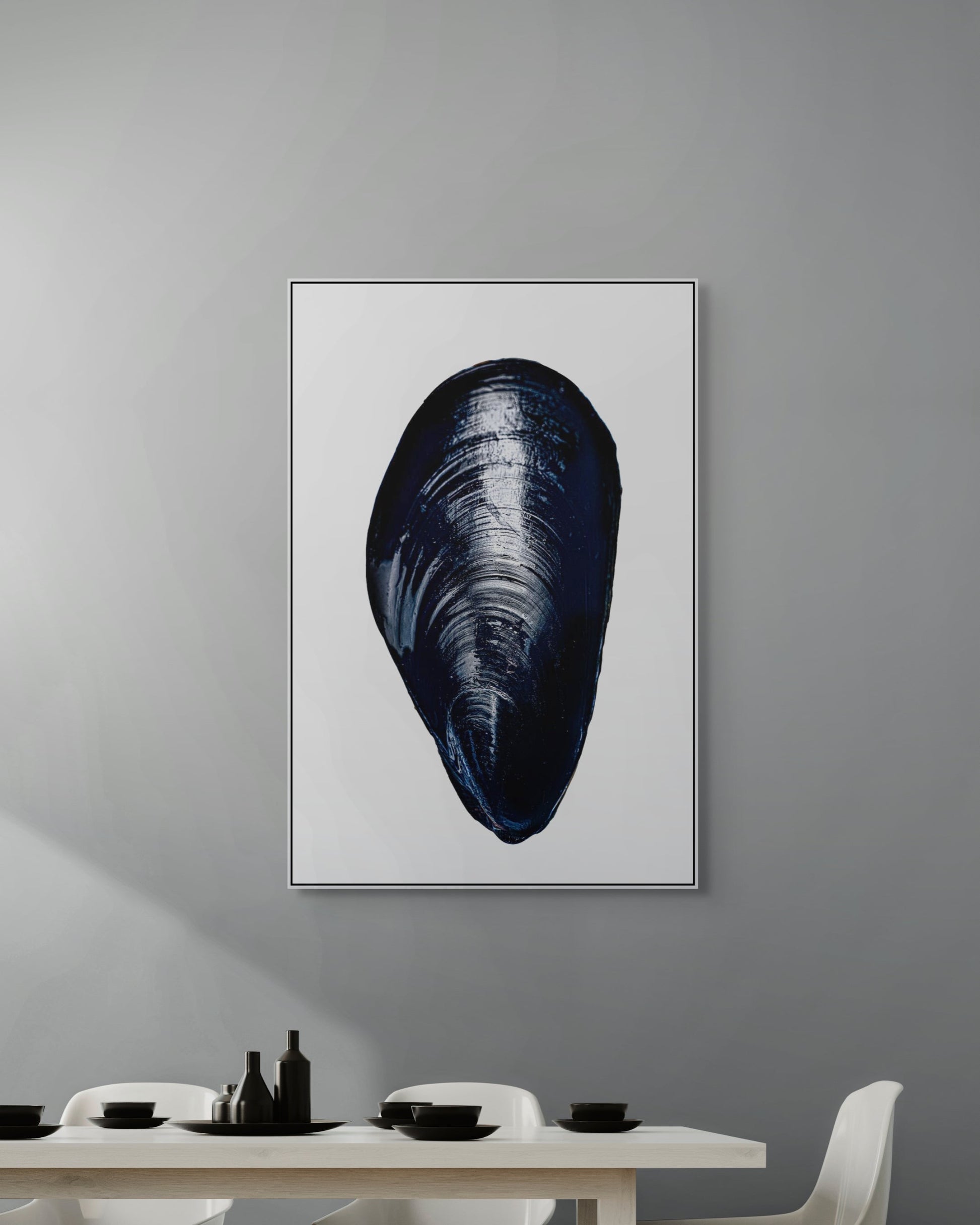 Framed artwork of a mussel shell on a gray wall above a dining table.