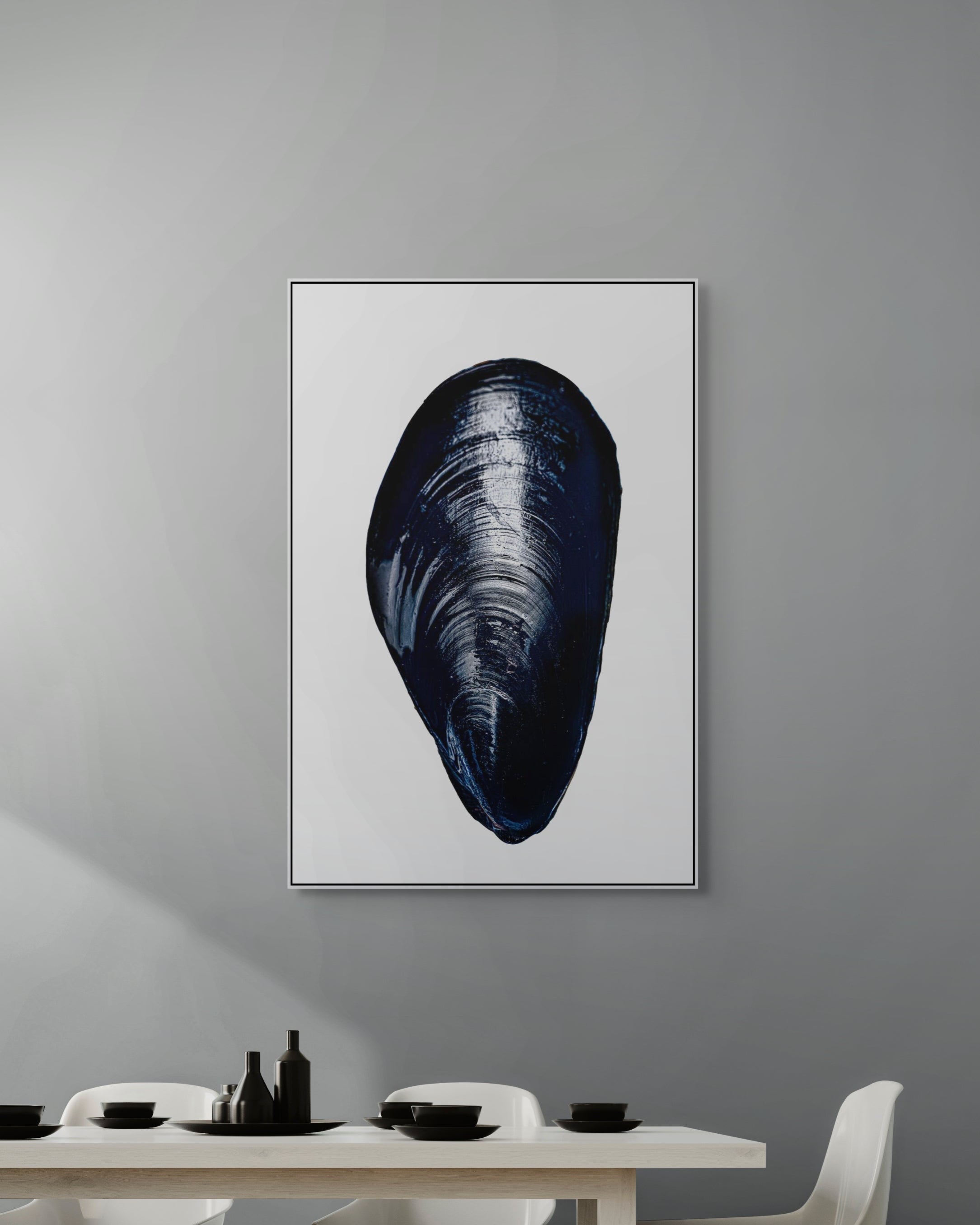 Framed artwork of a mussel shell on a gray wall above a dining table.