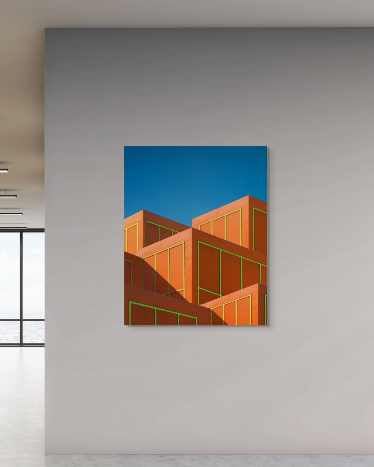 Abstract art print of geometric shapes on a blue background, hanging on a gray wall.