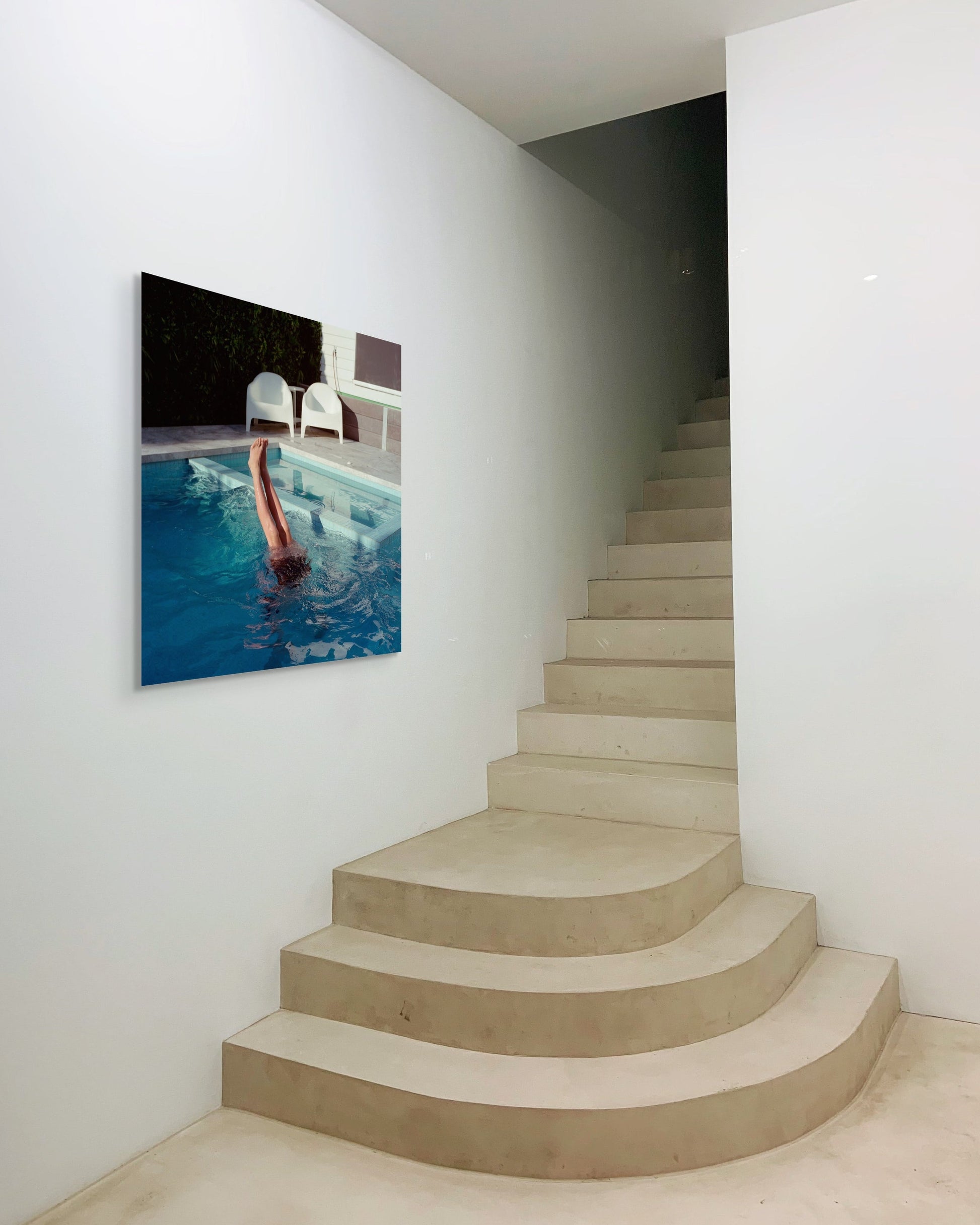 Staircase leading with a metal print of a pool scene on the wall.