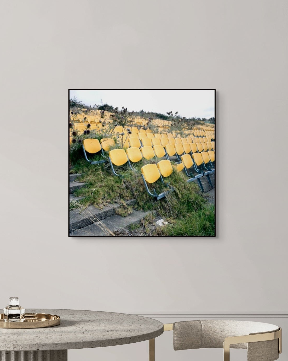Framed photograph of yellow stadium seats on a gray wall above a table.