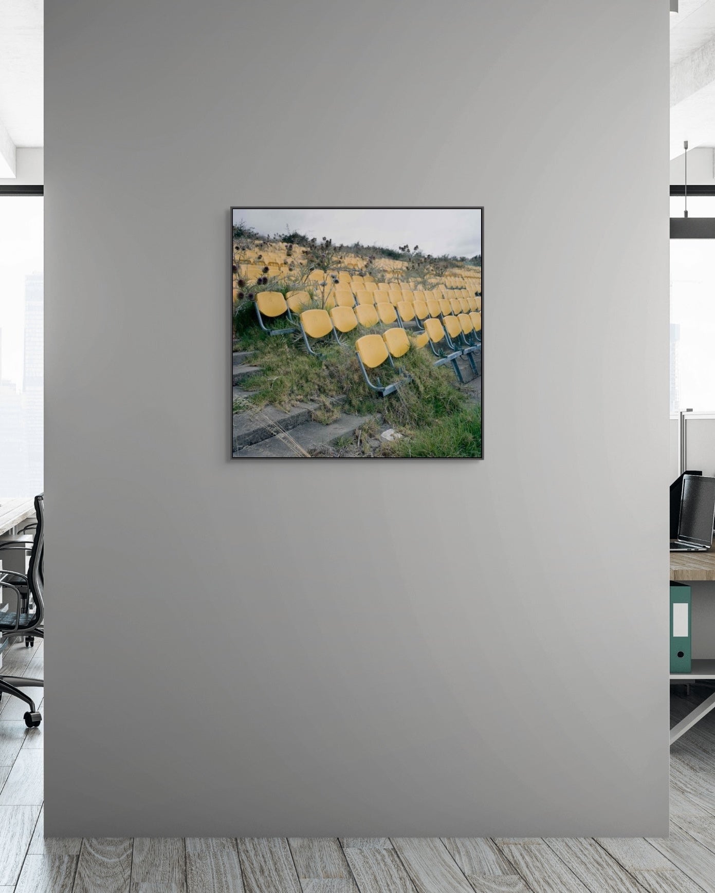 Modern office interior with a framed picture of yellow chairs on a gray wall.