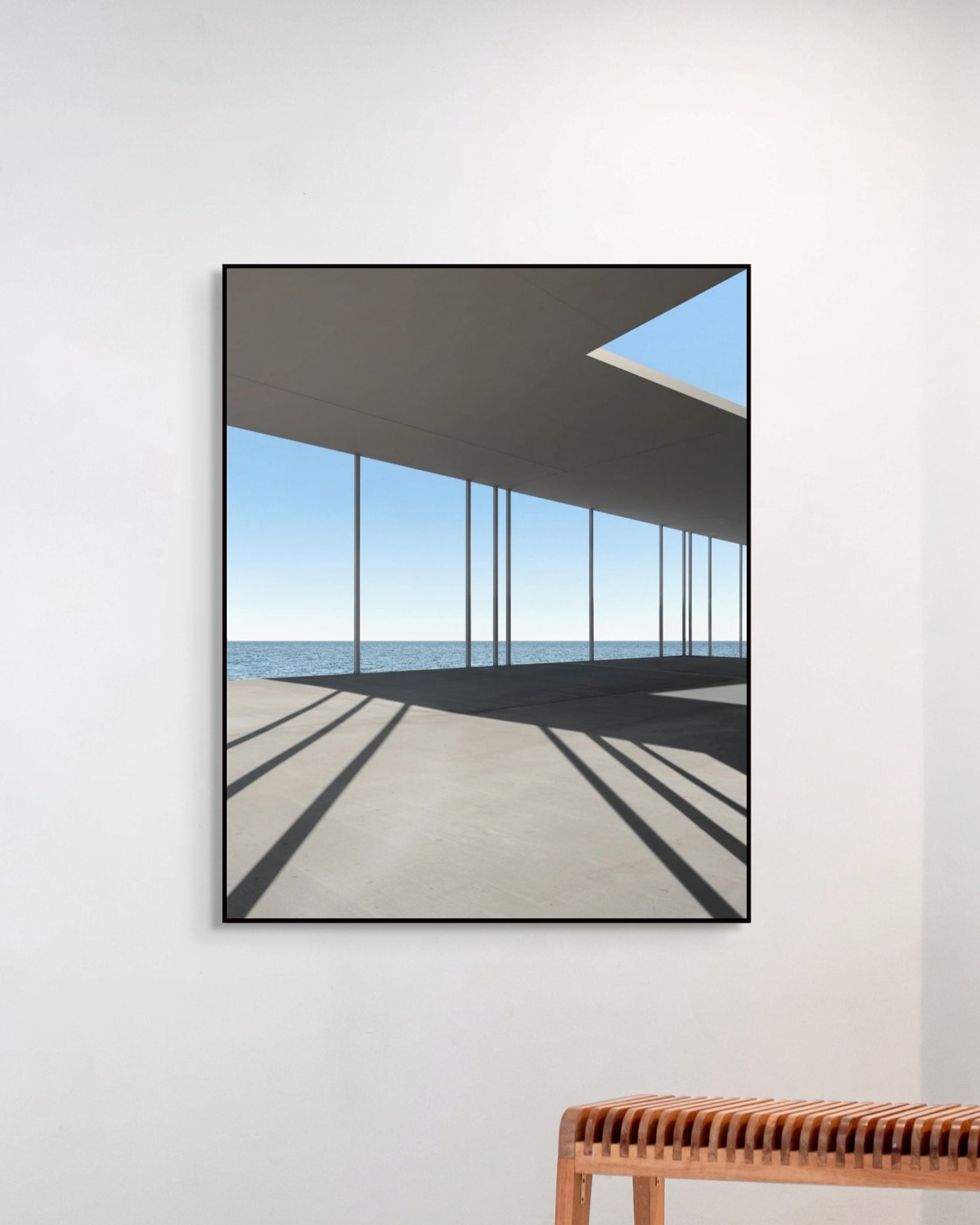 Framed abstract art on a white wall with a wooden bench below