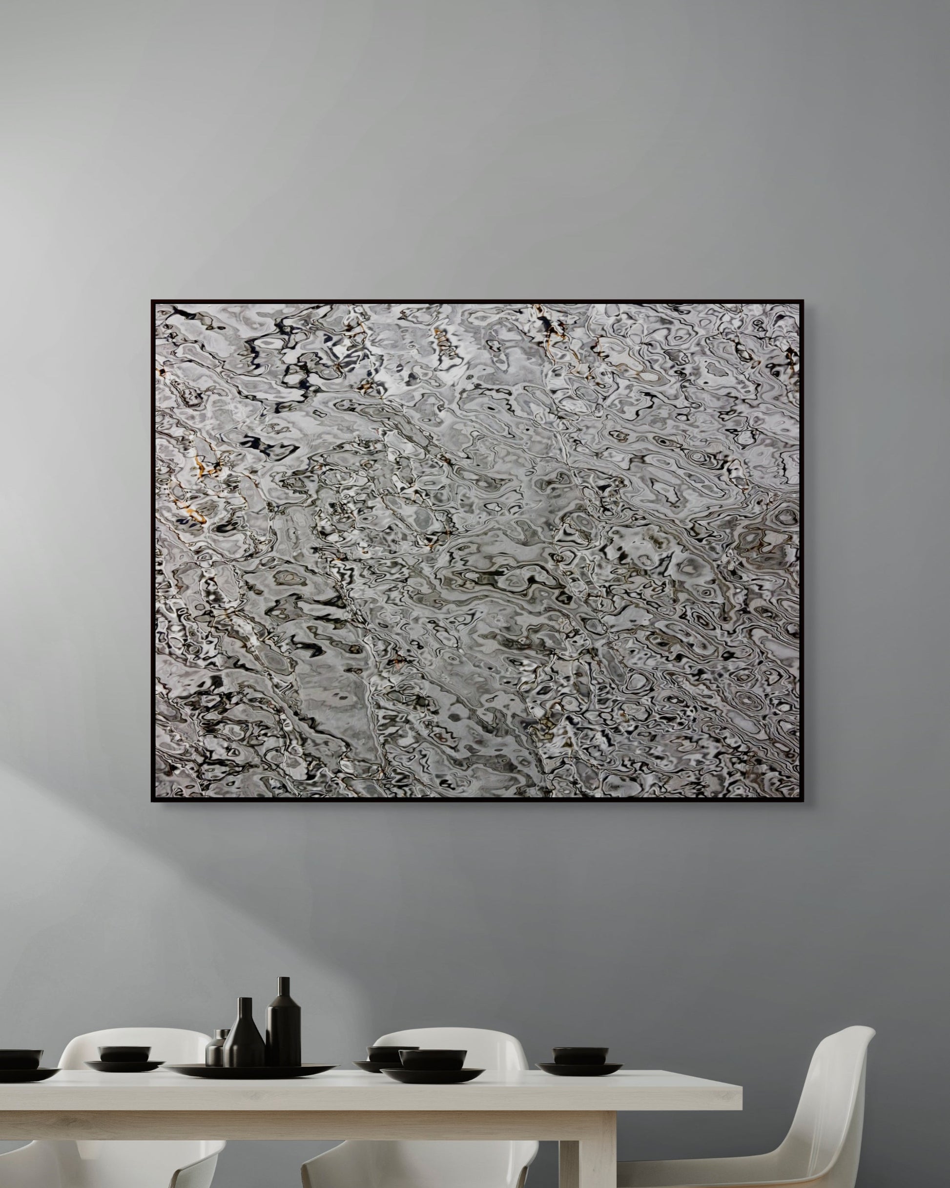 Abstract art piece on a gray wall above a dining table with white chairs.