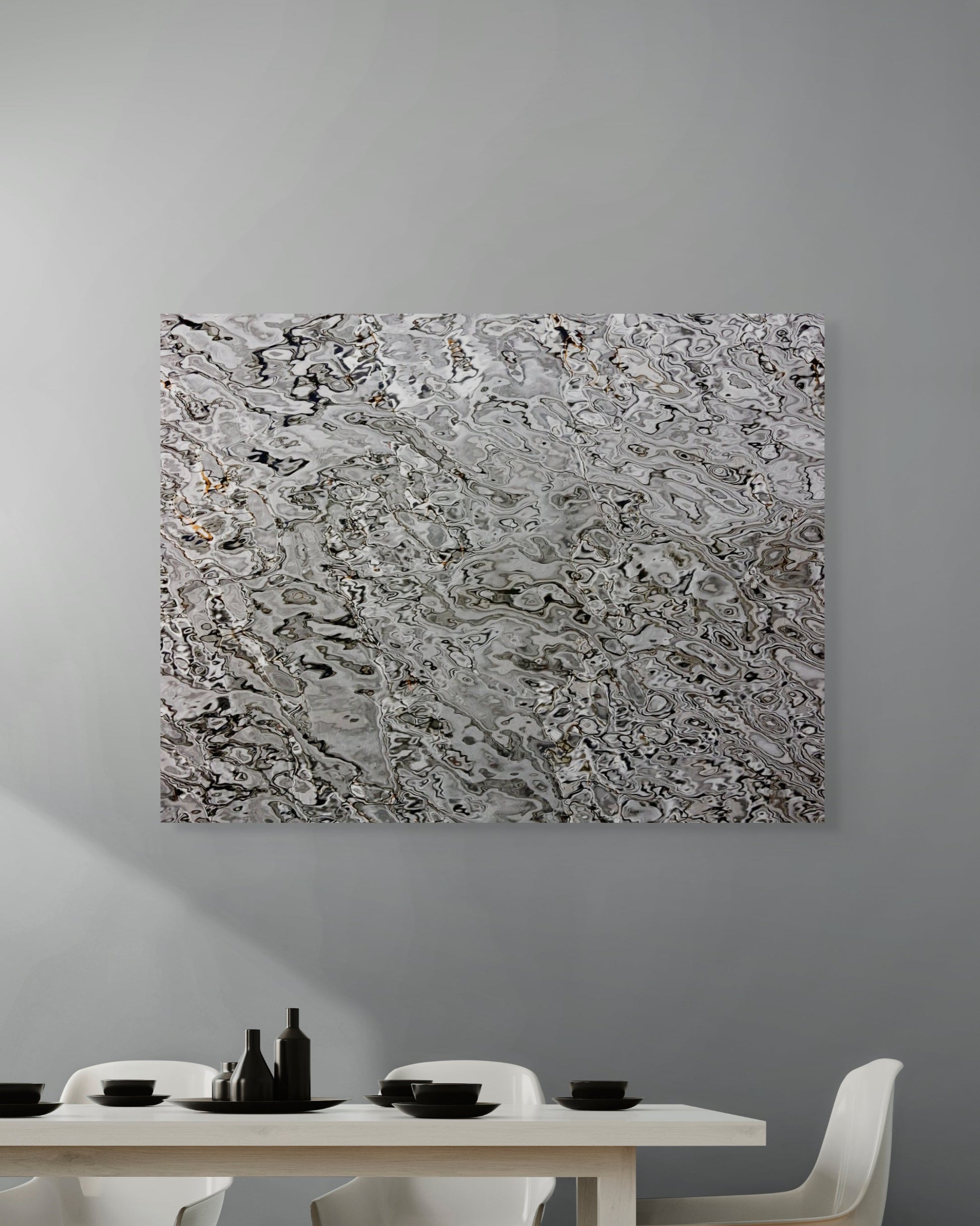 Abstract metal print on a gray wall above a dining table with white chairs.