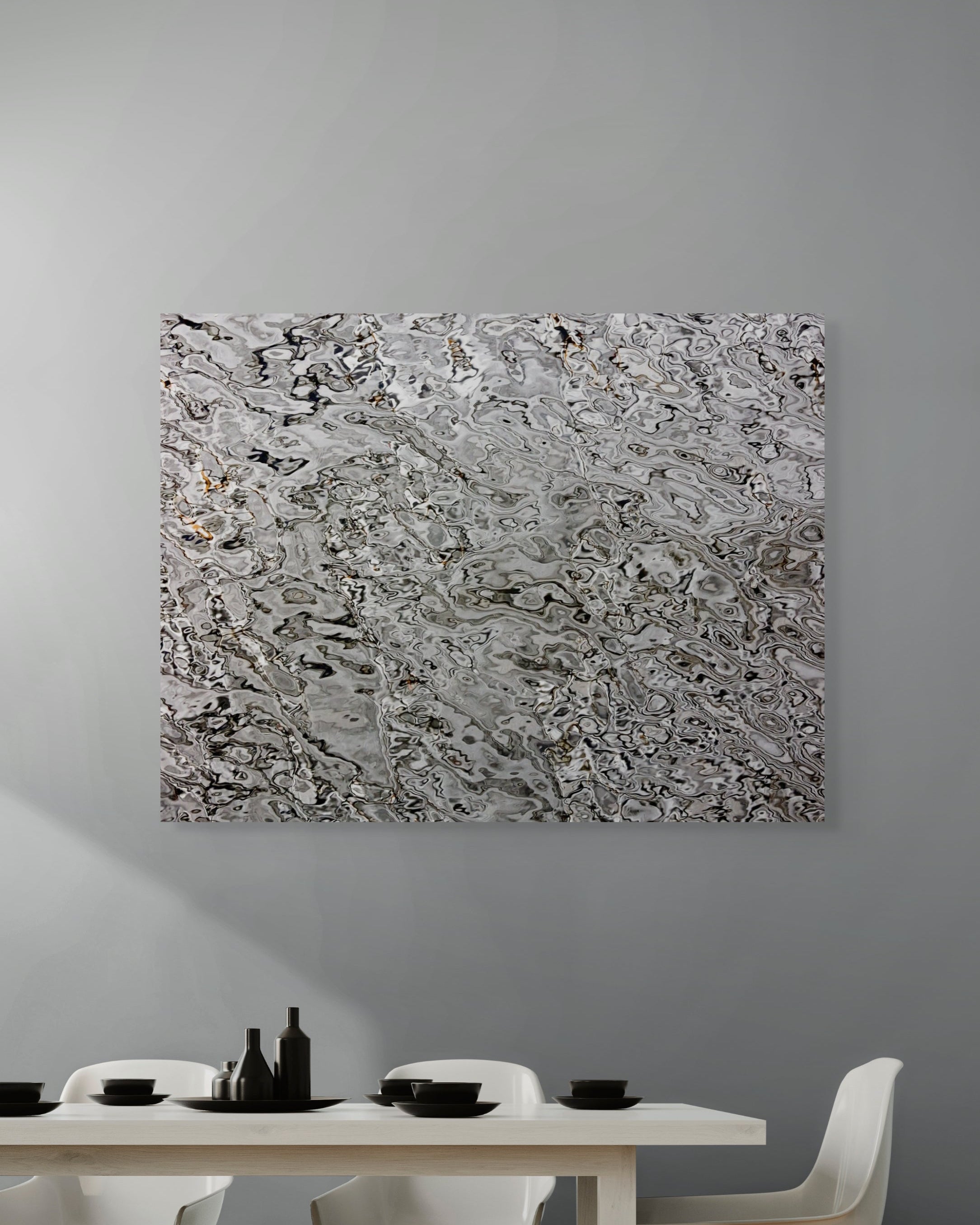 Abstract metal print on a gray wall above a dining table with white chairs.
