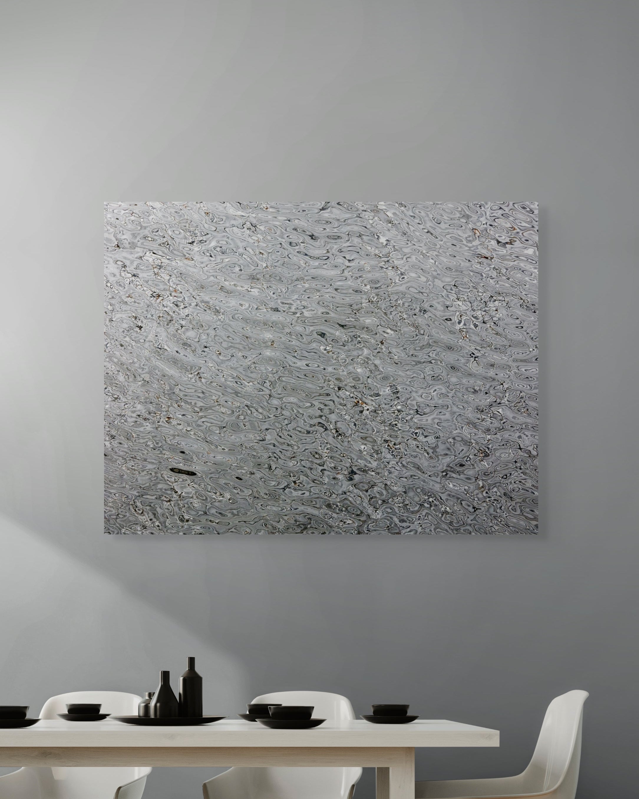 Abstract art piece on a gray wall above a dining table with white chairs.