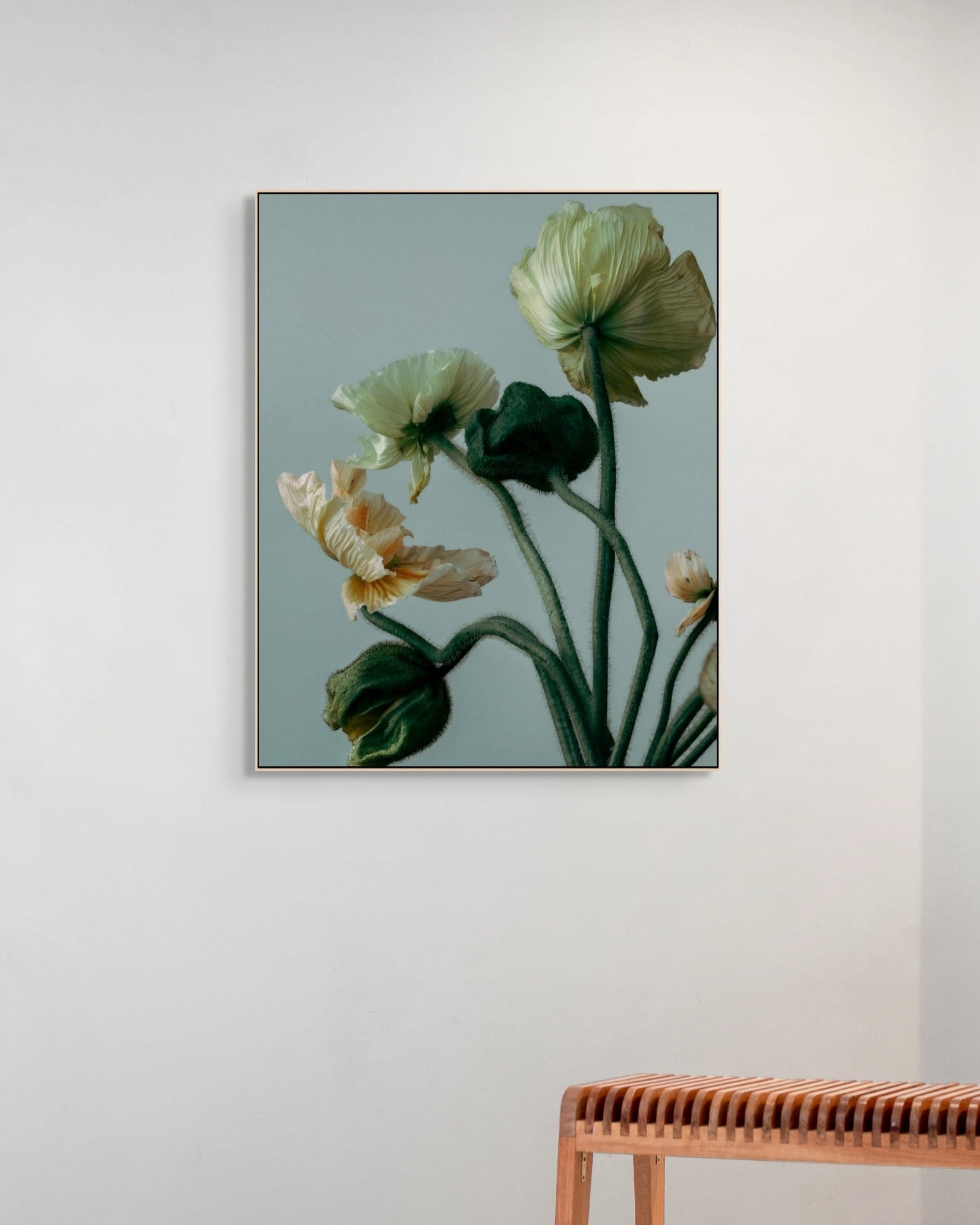 Framed floral artwork on a wall with a wooden bench below.