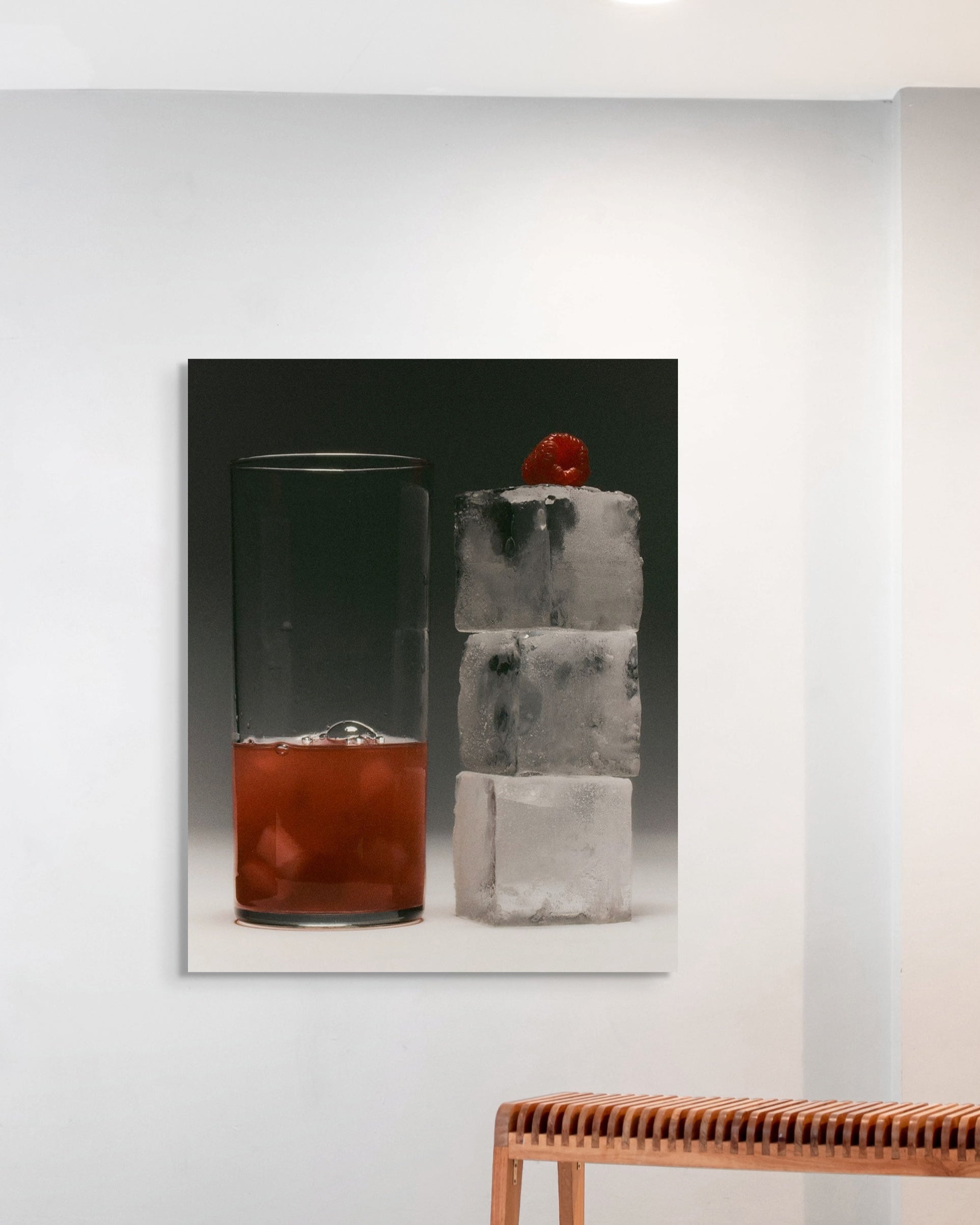 Cocktail in a glass with ice and a red cherry on a white wall.