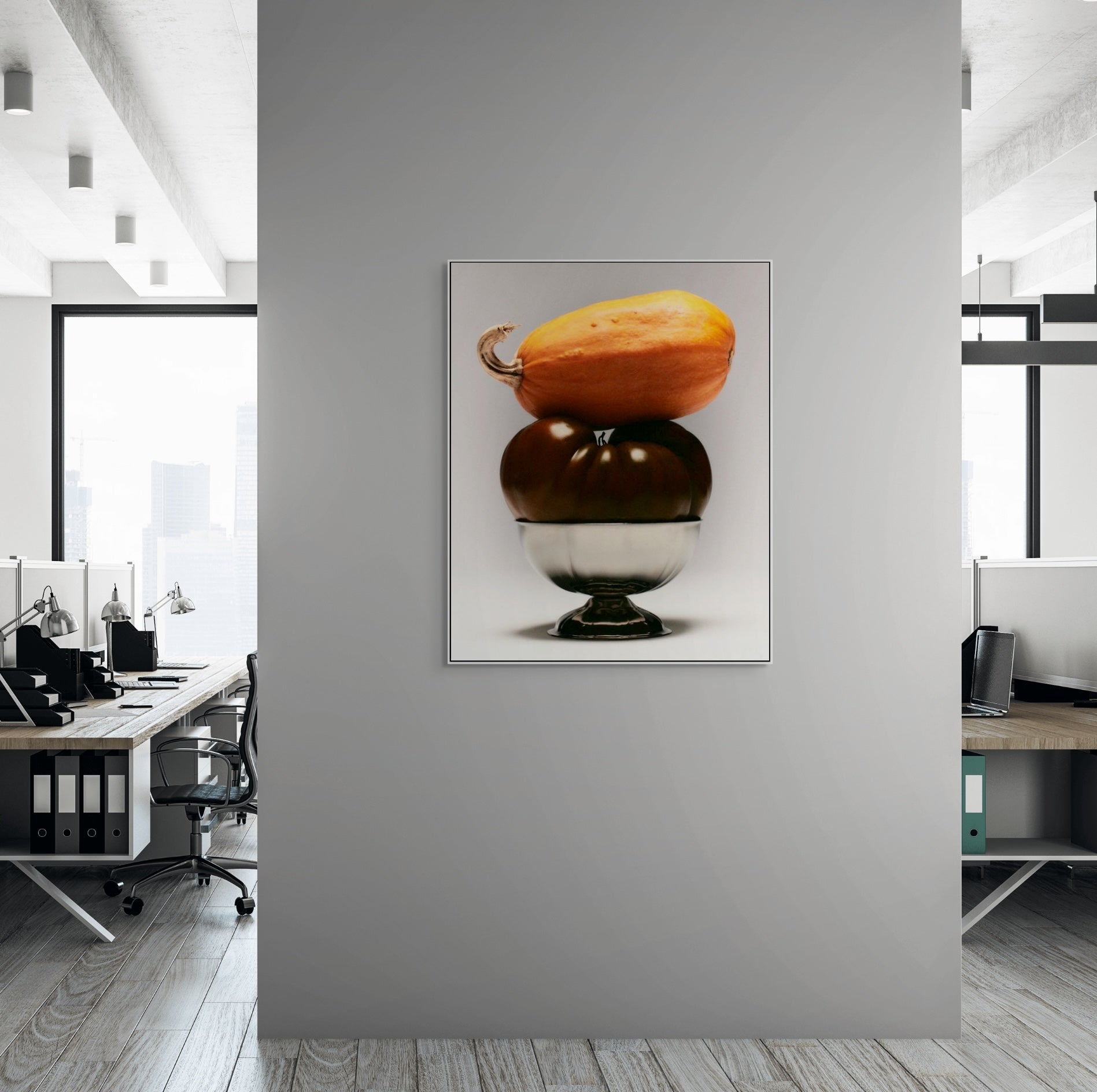 Framed artwork of two stacked pumpkins on a gray wall in an office setting.