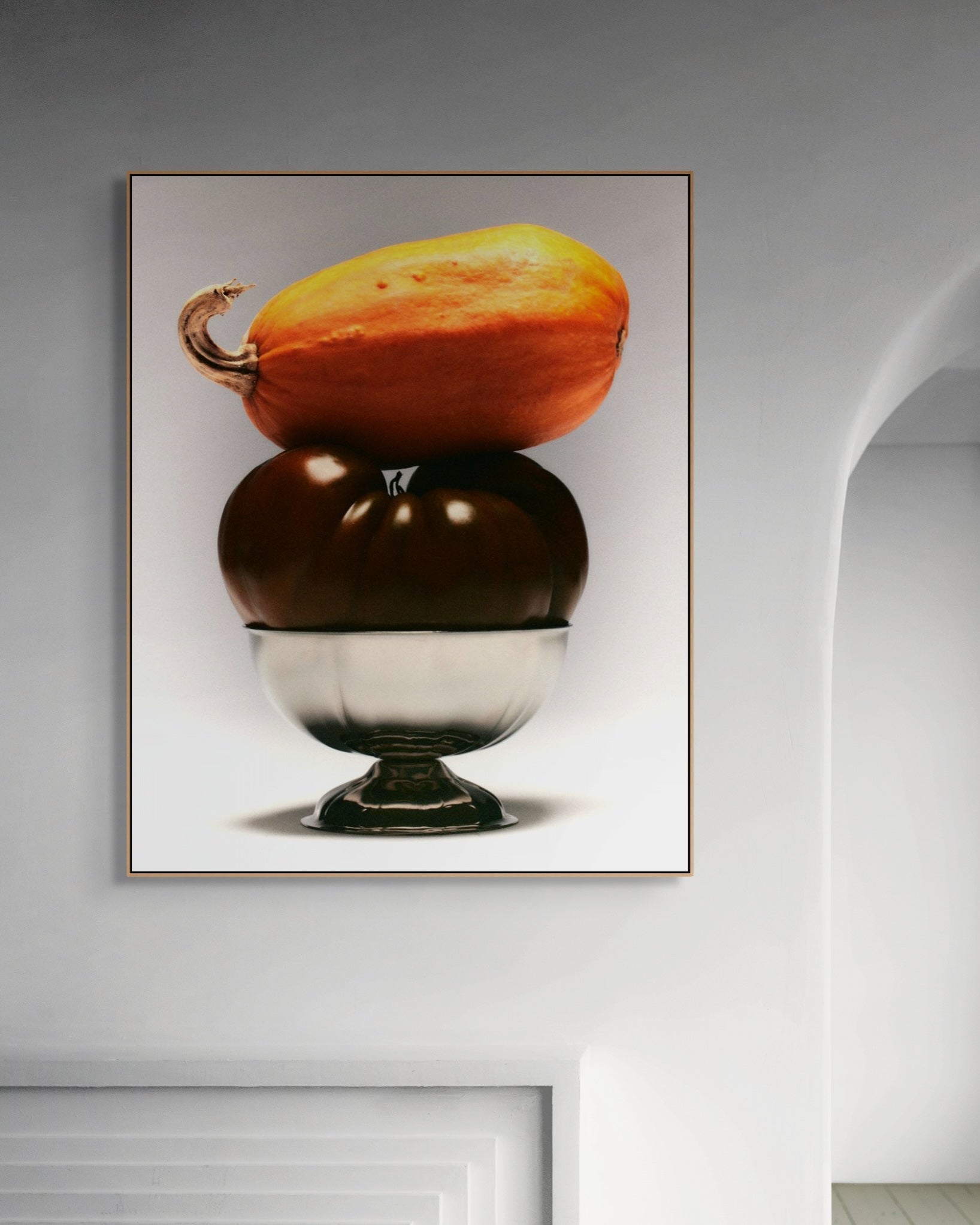 Framed artwork of stacked pumpkins on a neutral wall