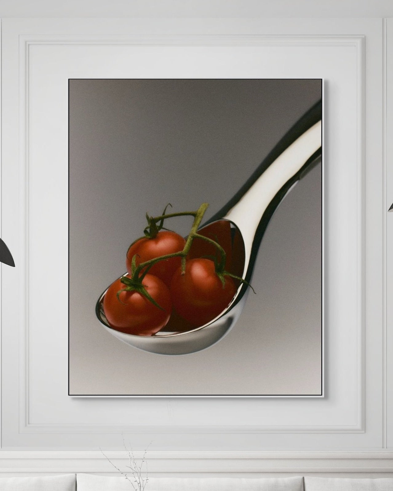Framed artwork of a spoon with tomatoes on a white wall.