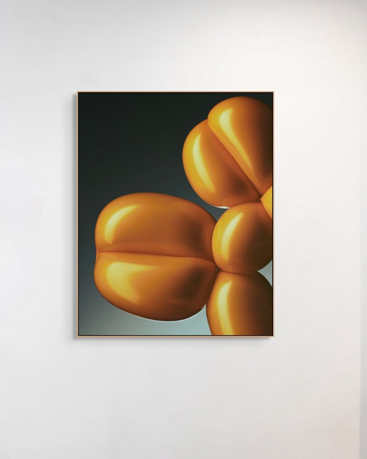 Framed artwork of a yellow abstract balloon shape on a white wall.