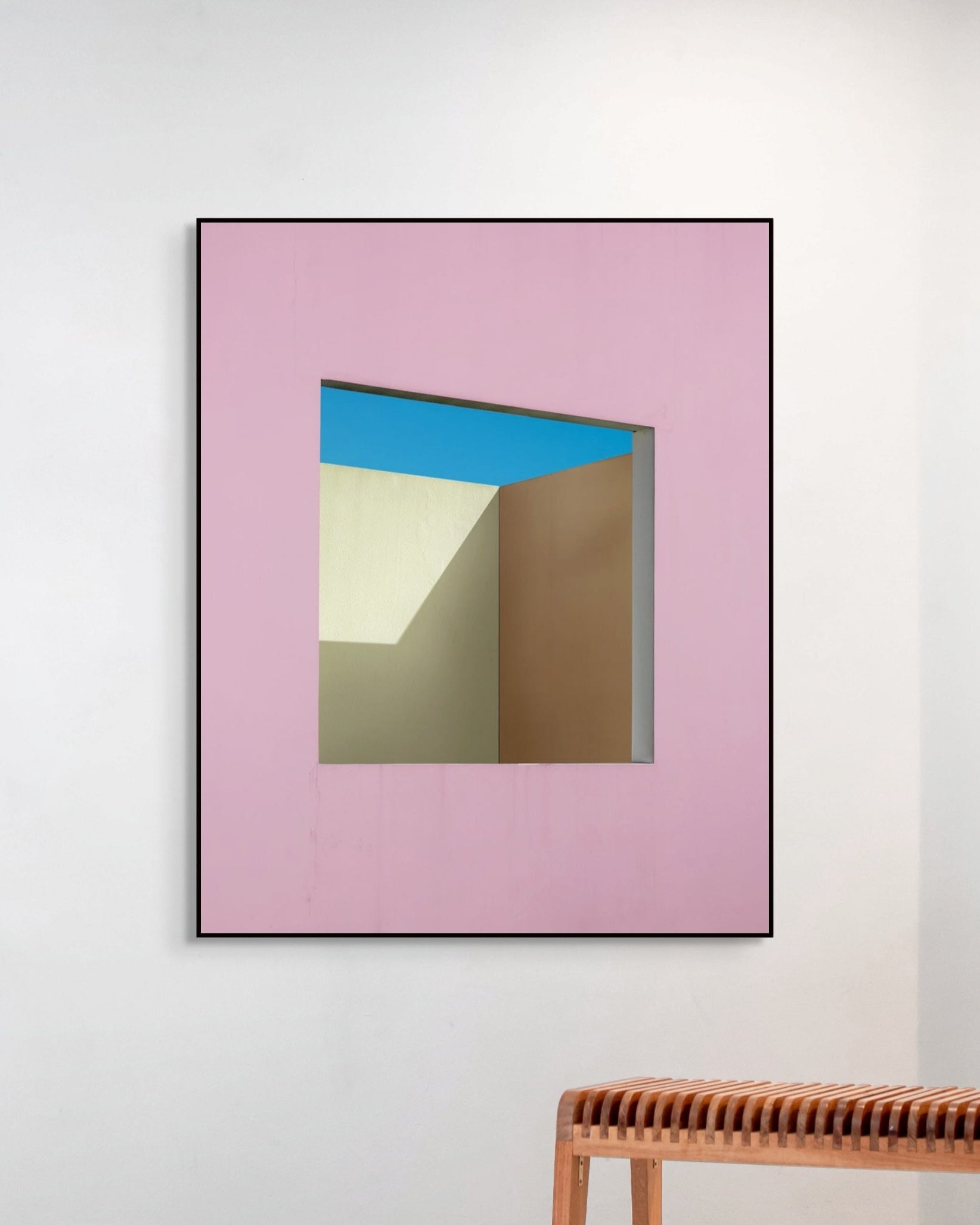 Framed abstract artwork with pink border and geometric shapes on a white wall.