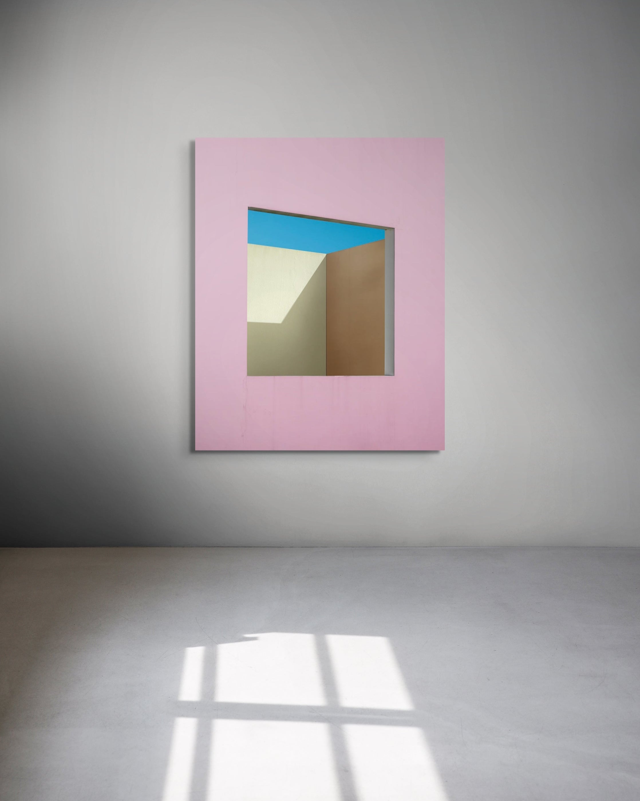 Framed abstract artwork with a pink border and colorful interior on a gray wall.