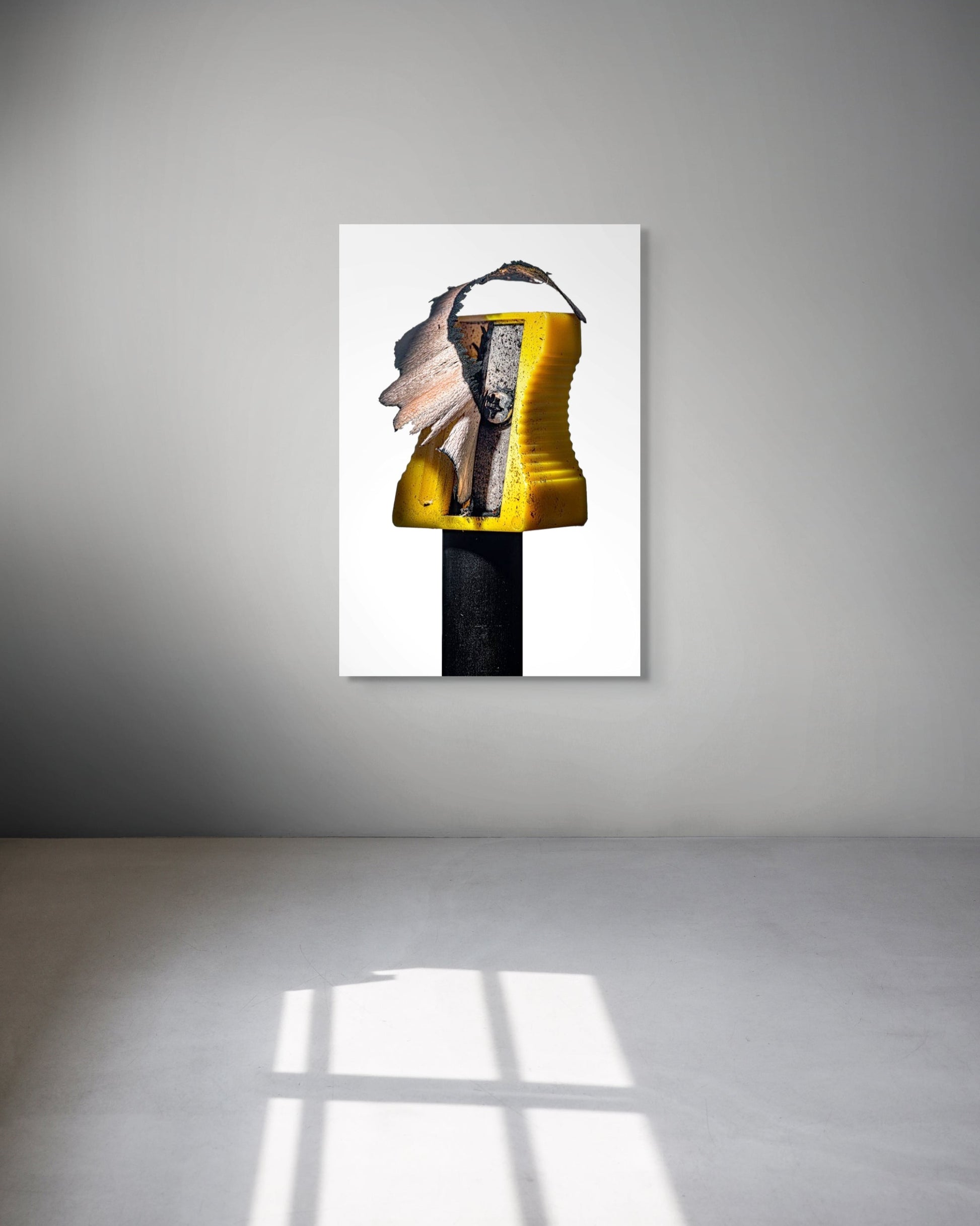 Abstract art piece on a white wall with a gray floor