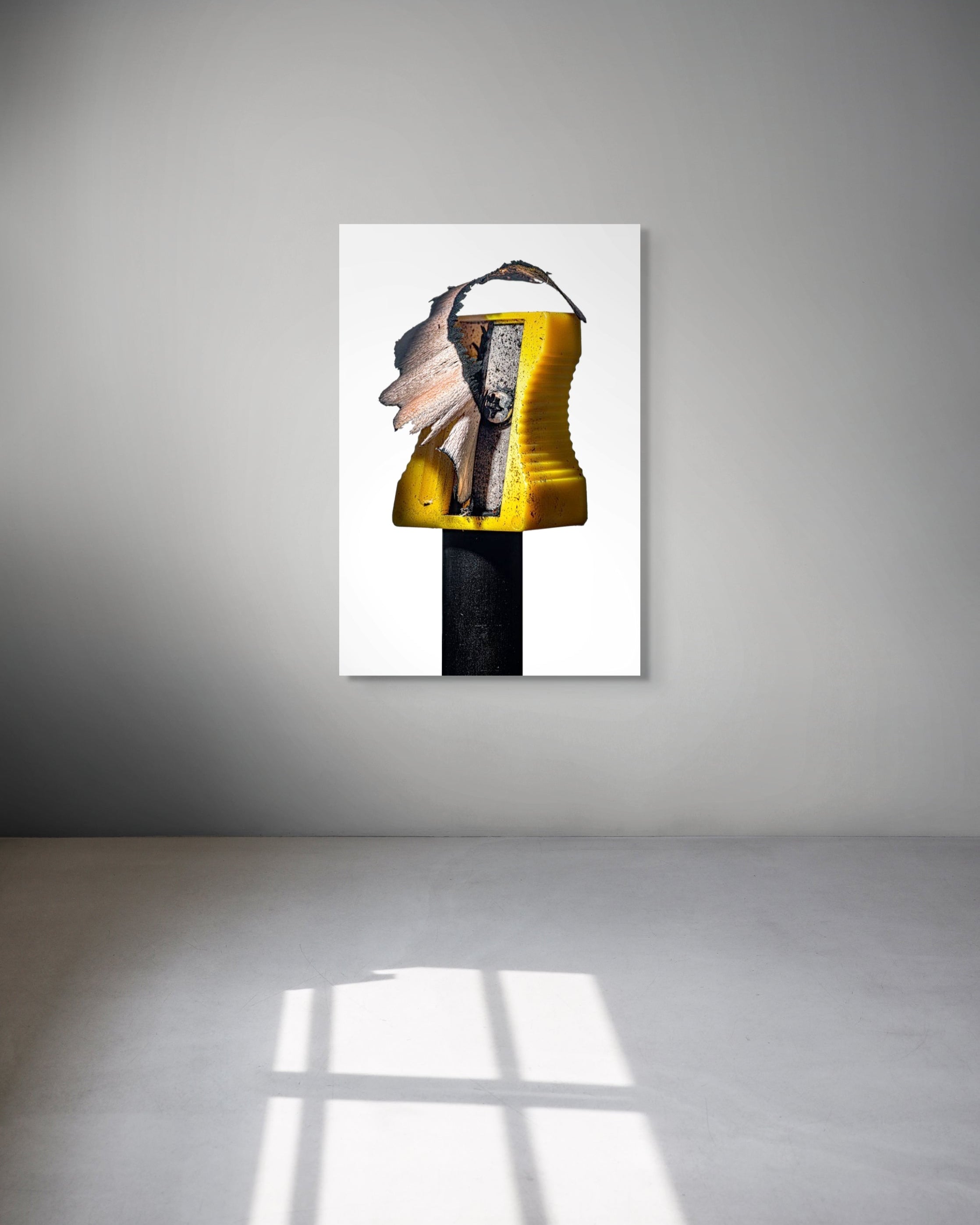 Abstract art piece on a white wall with a gray floor