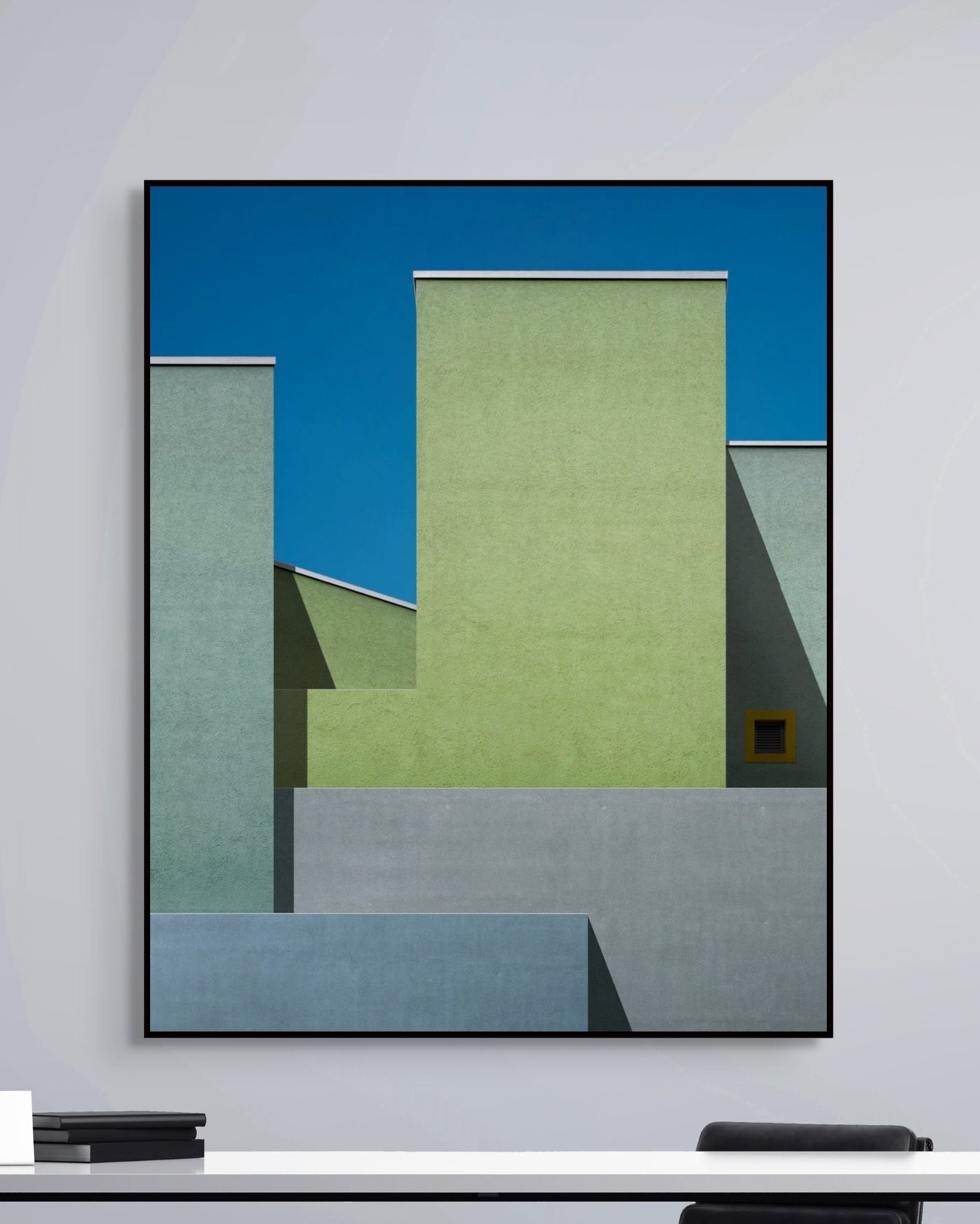 Abstract art piece with geometric shapes in blue and green on a white wall.