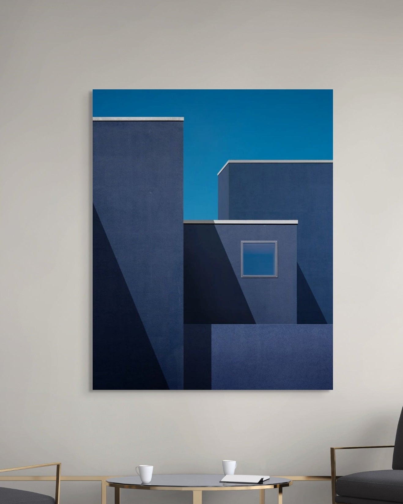 Abstract blue artwork on a gray wall above a modern living room setup.