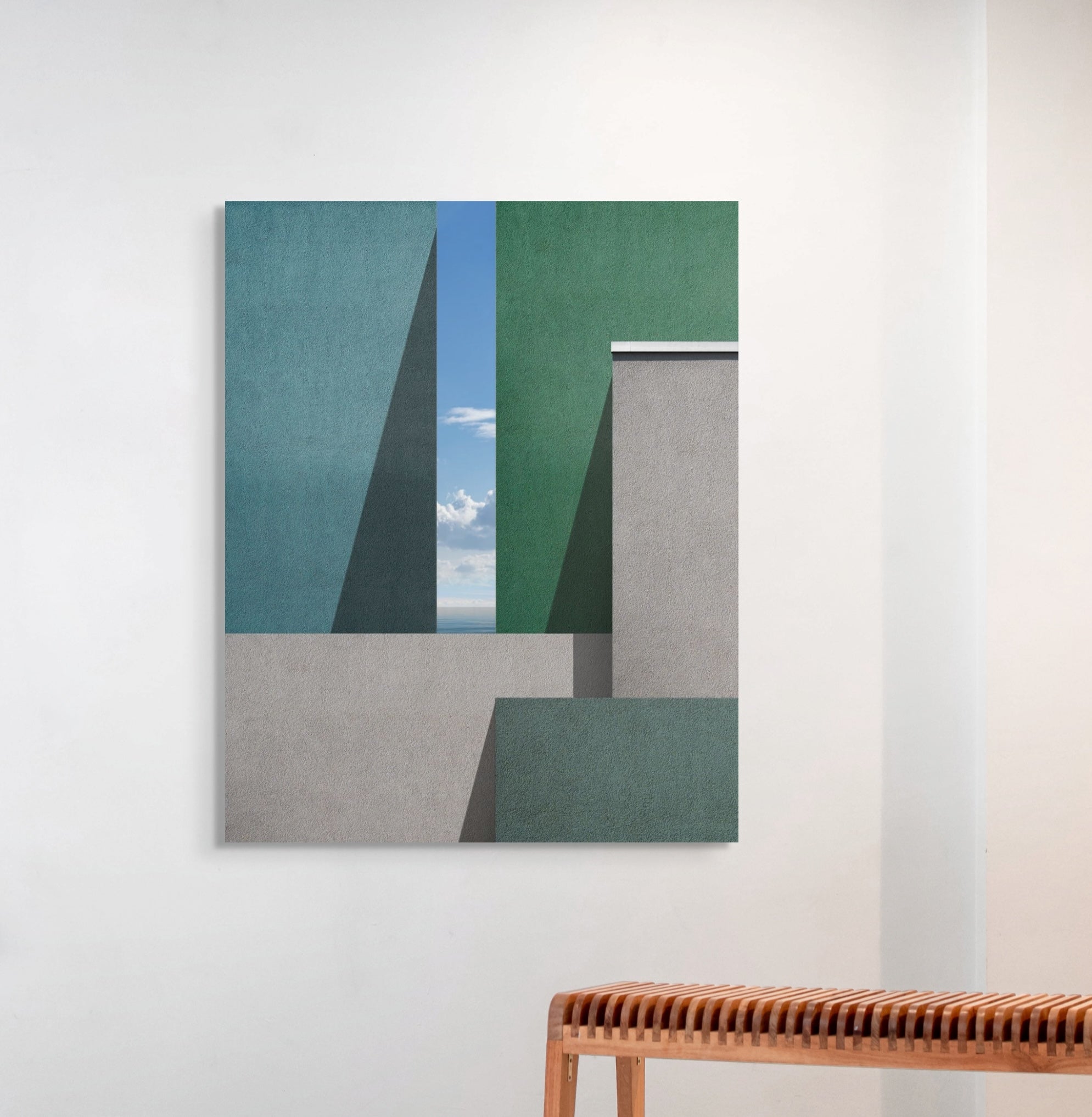 Abstract art piece on a white wall with a wooden bench below