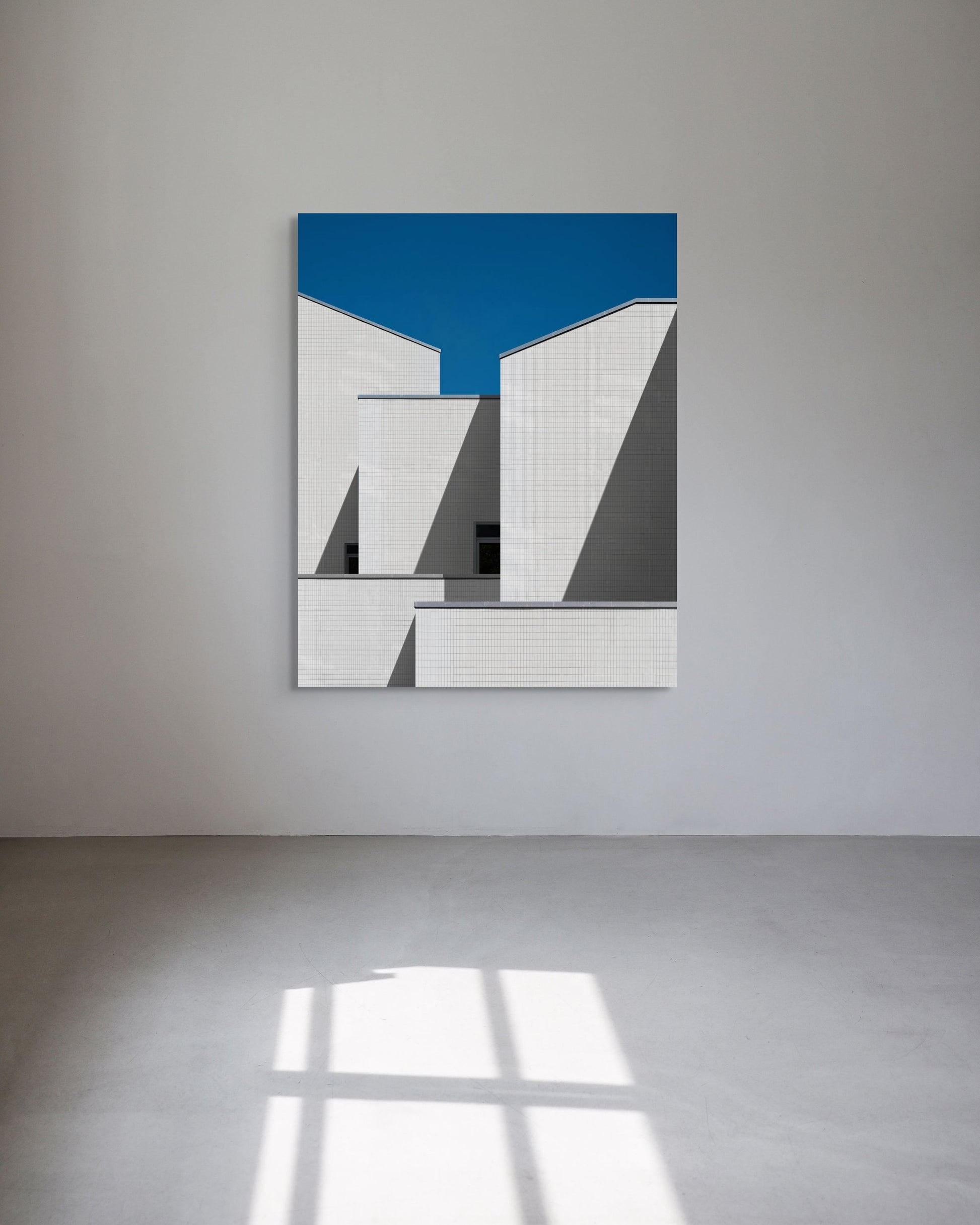 Abstract art piece with geometric shapes on a blue background, mounted on a white wall.