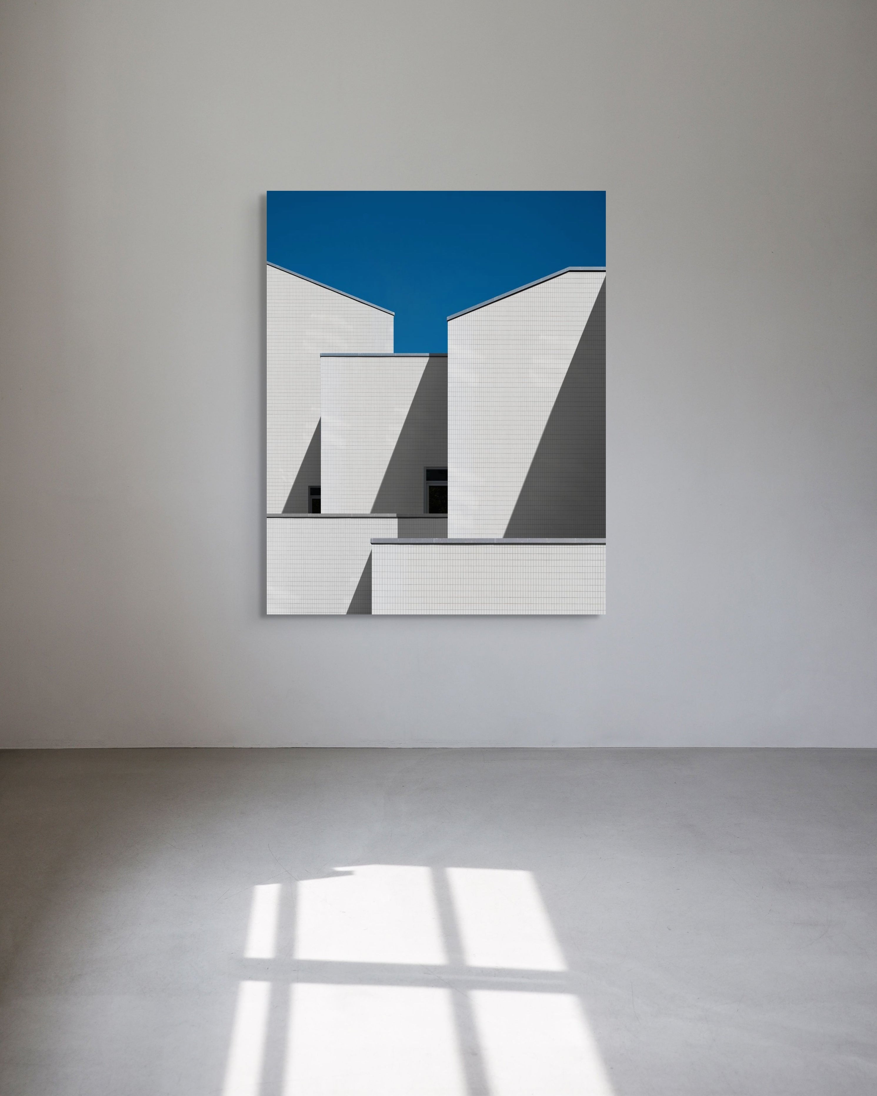 Abstract art piece with geometric shapes on a blue background, mounted on a white wall.