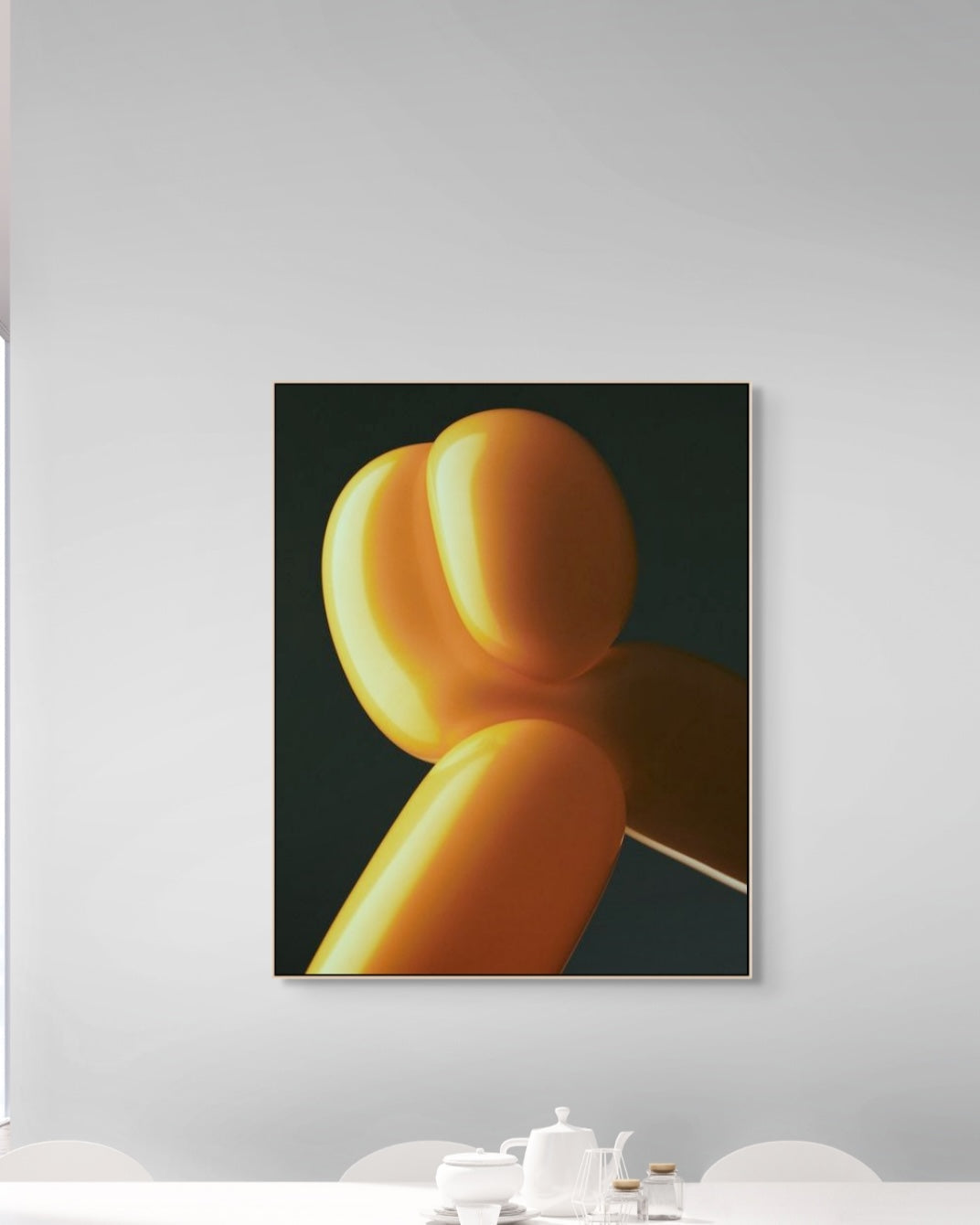 Framed artwork of a yellow balloon sculpture on a white wall.