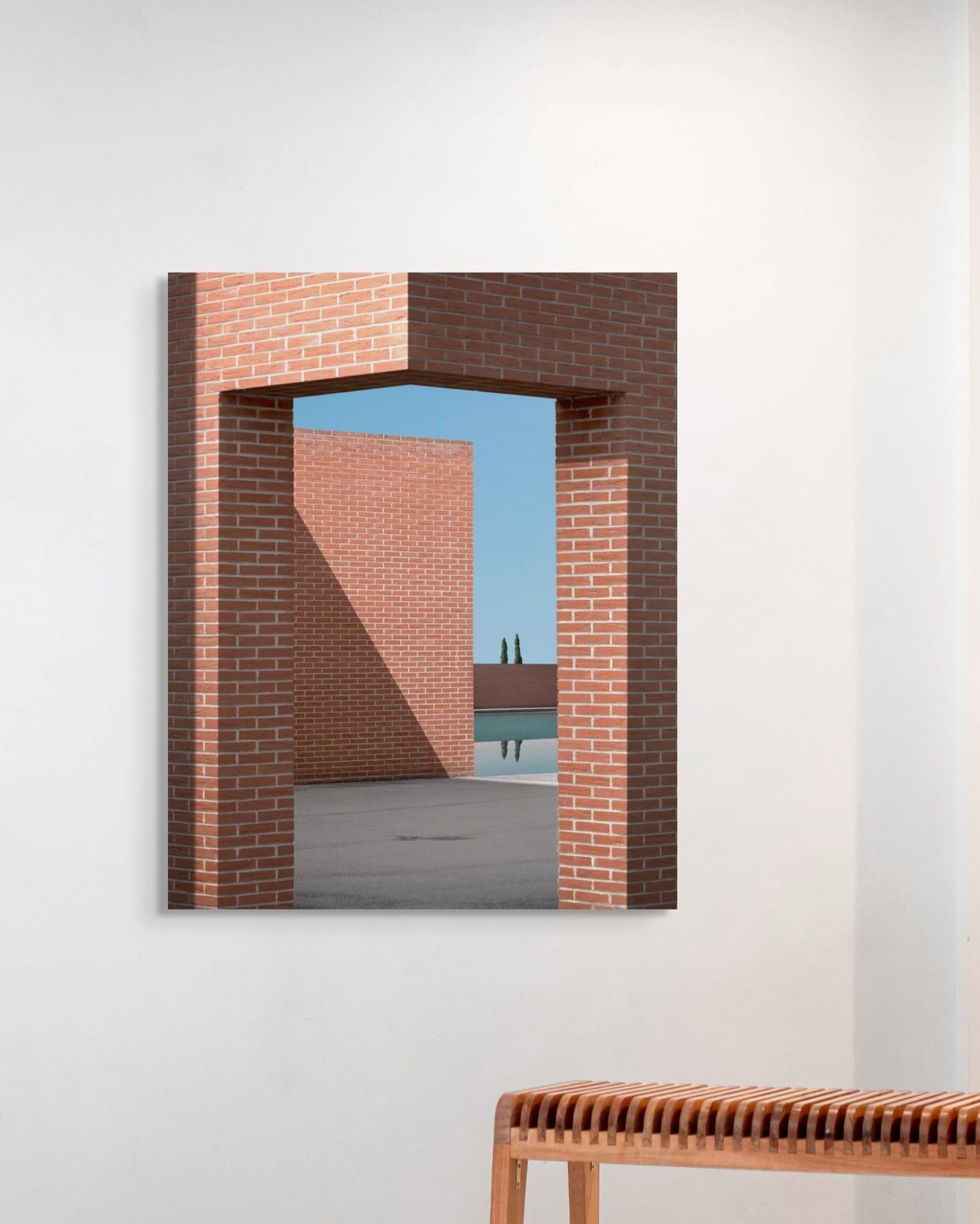 Framed photograph of a brick archway with a view of a lake and mountains on a white wall.