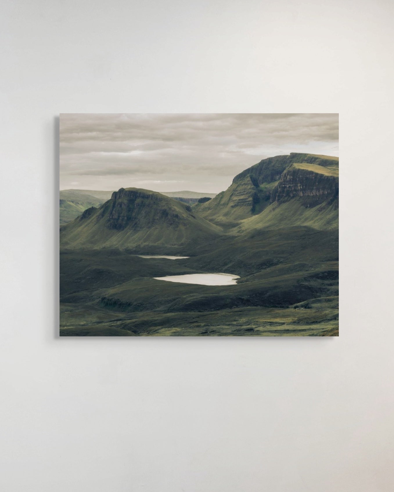 Scenic landscape photograph of a mountainous area with a lake on a white wall.