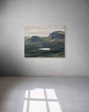 Scenic landscape photograph of a mountainous area with a lake on a white wall.