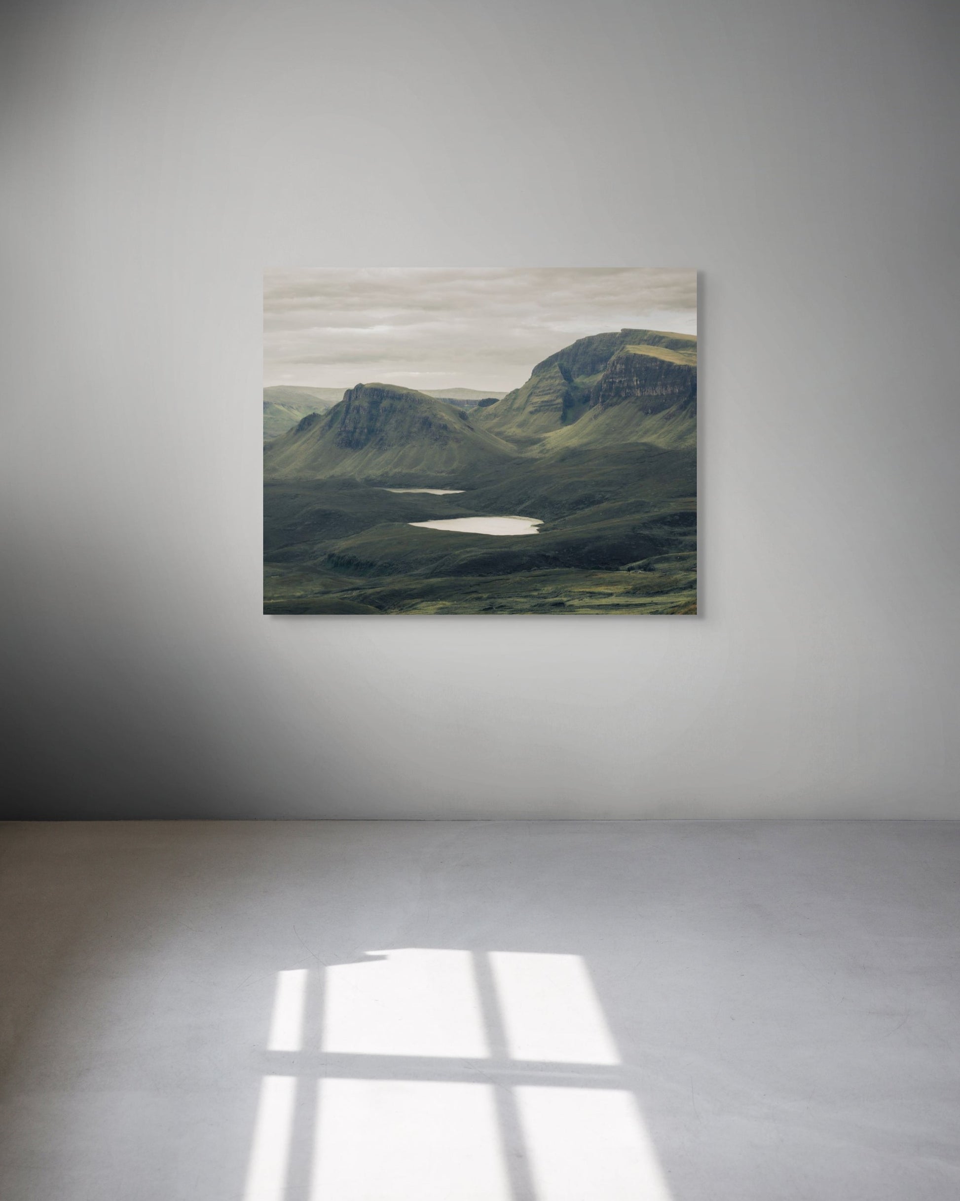 Scenic landscape photograph of a mountainous area with a lake on a white wall.