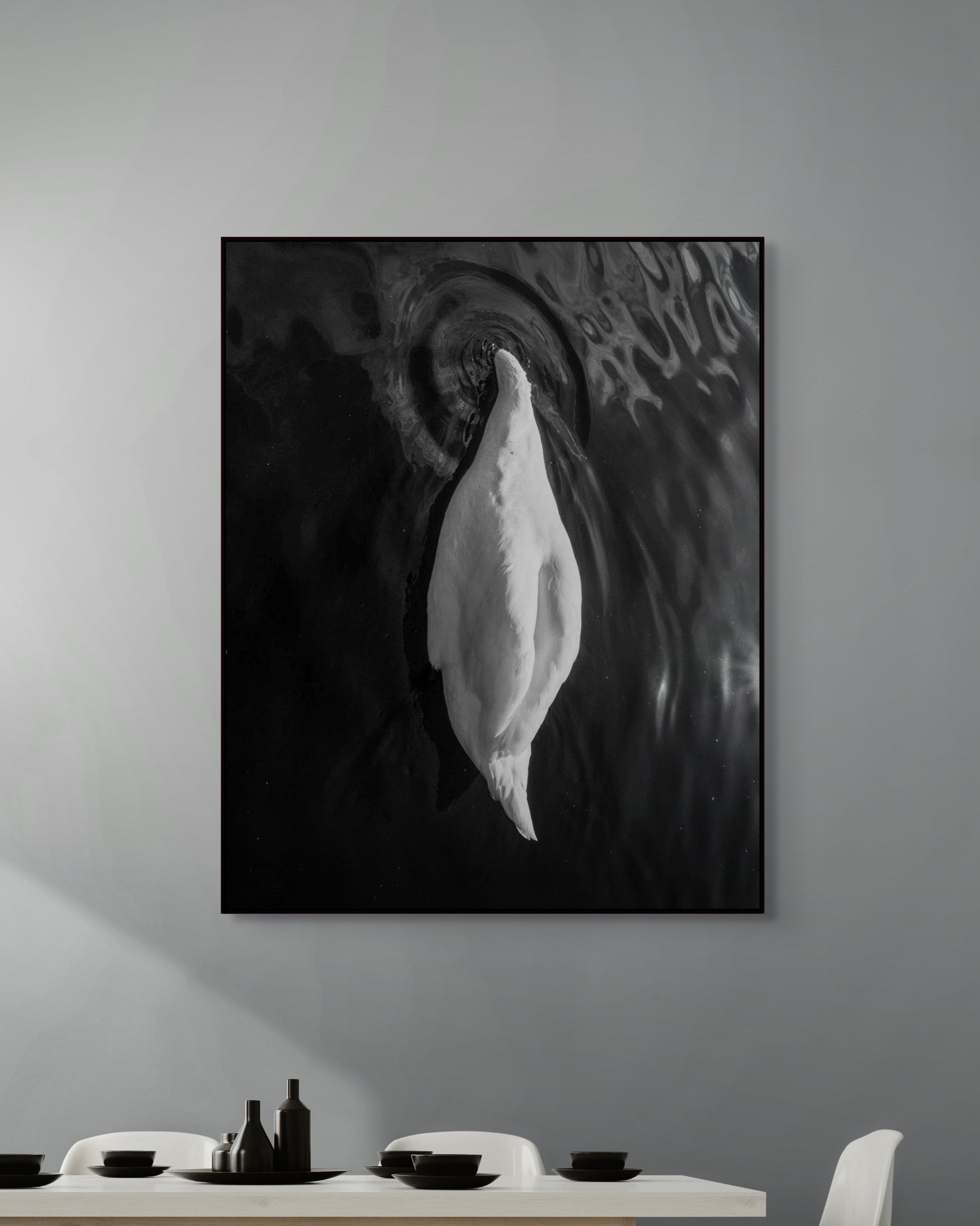 Framed black and white artwork on a wall above a dining table.