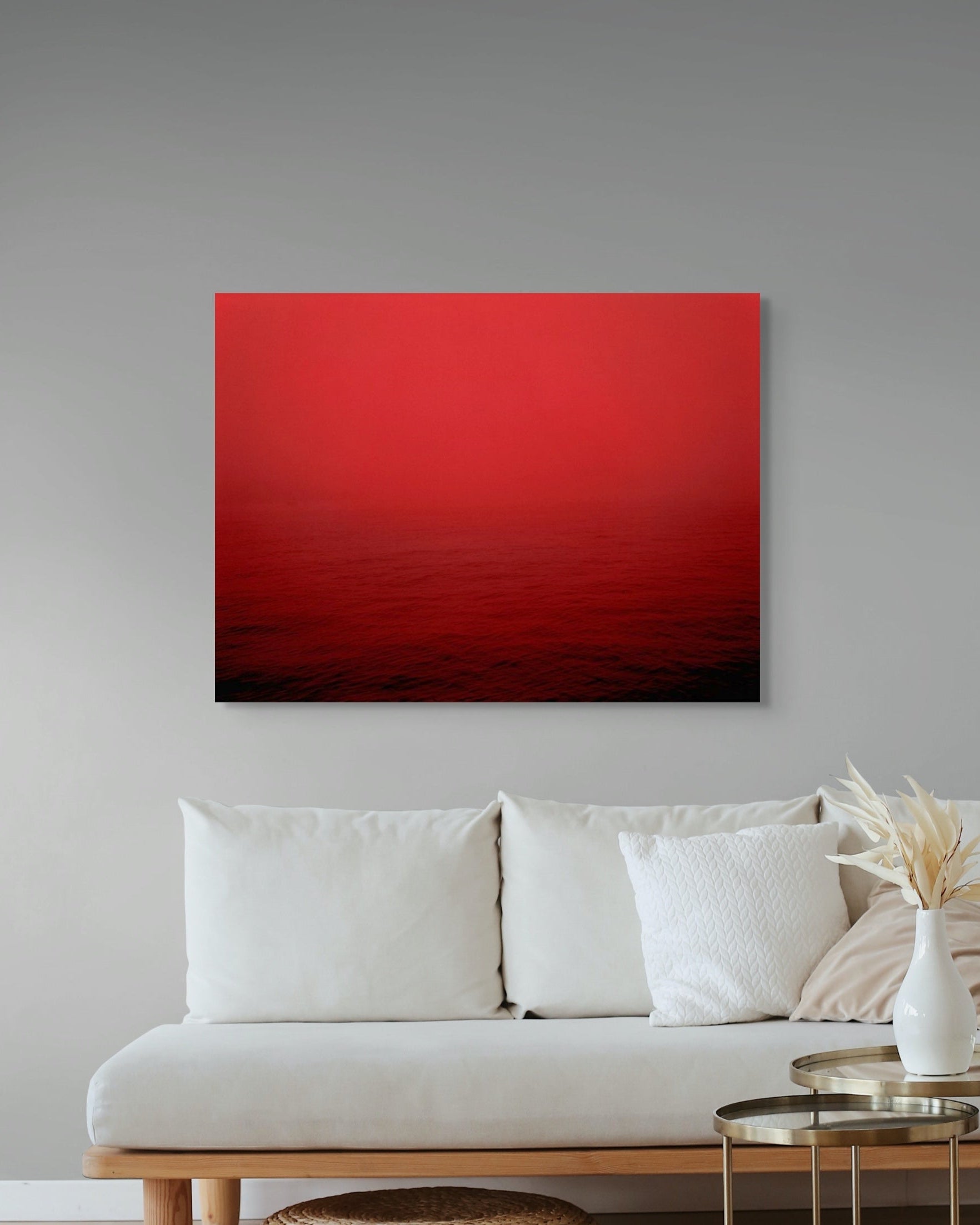 Red abstract metal print on a gray wall above a white sofa.