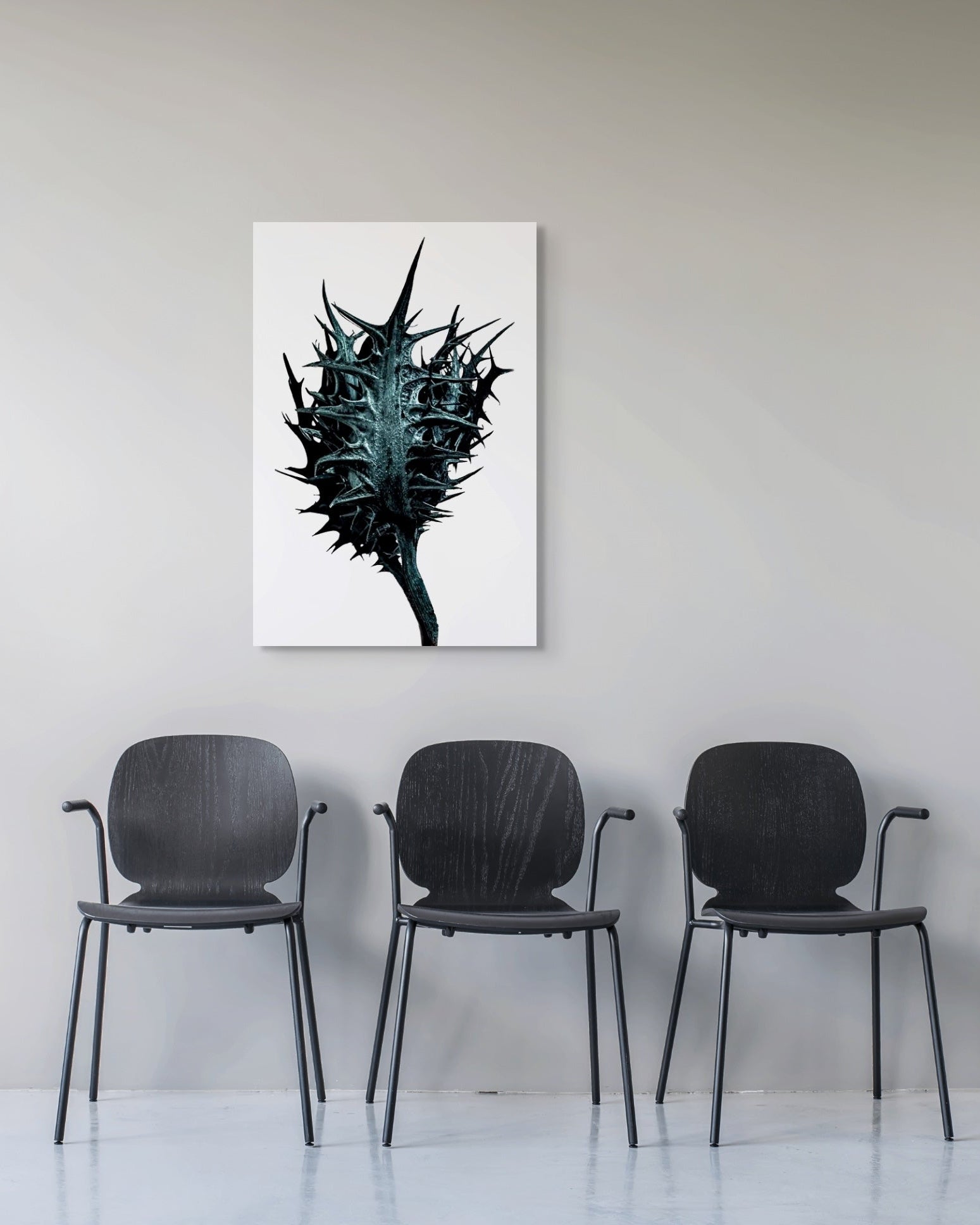 Three black chairs in a row with a large abstract metal print on the wall above them.