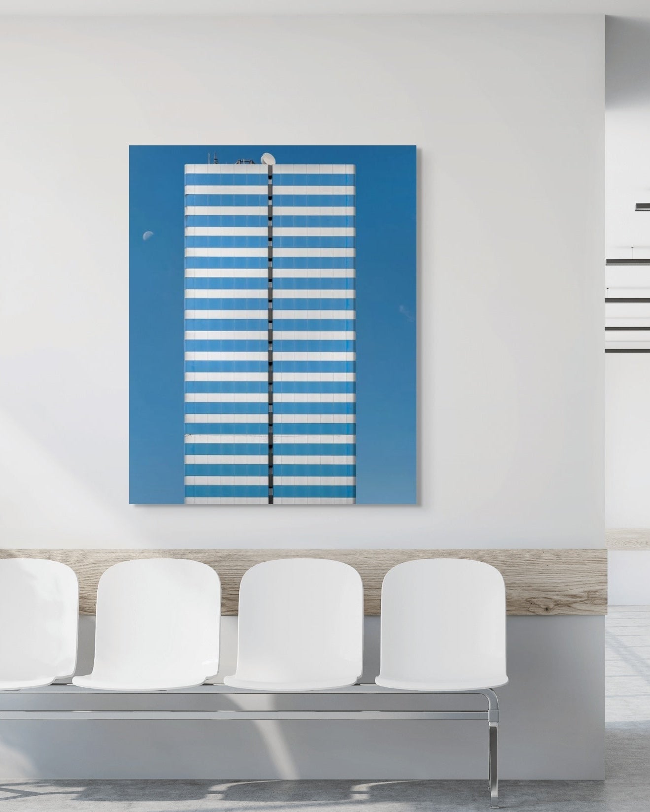 Modern waiting room with white chairs and a blue architectural print on the wall.
