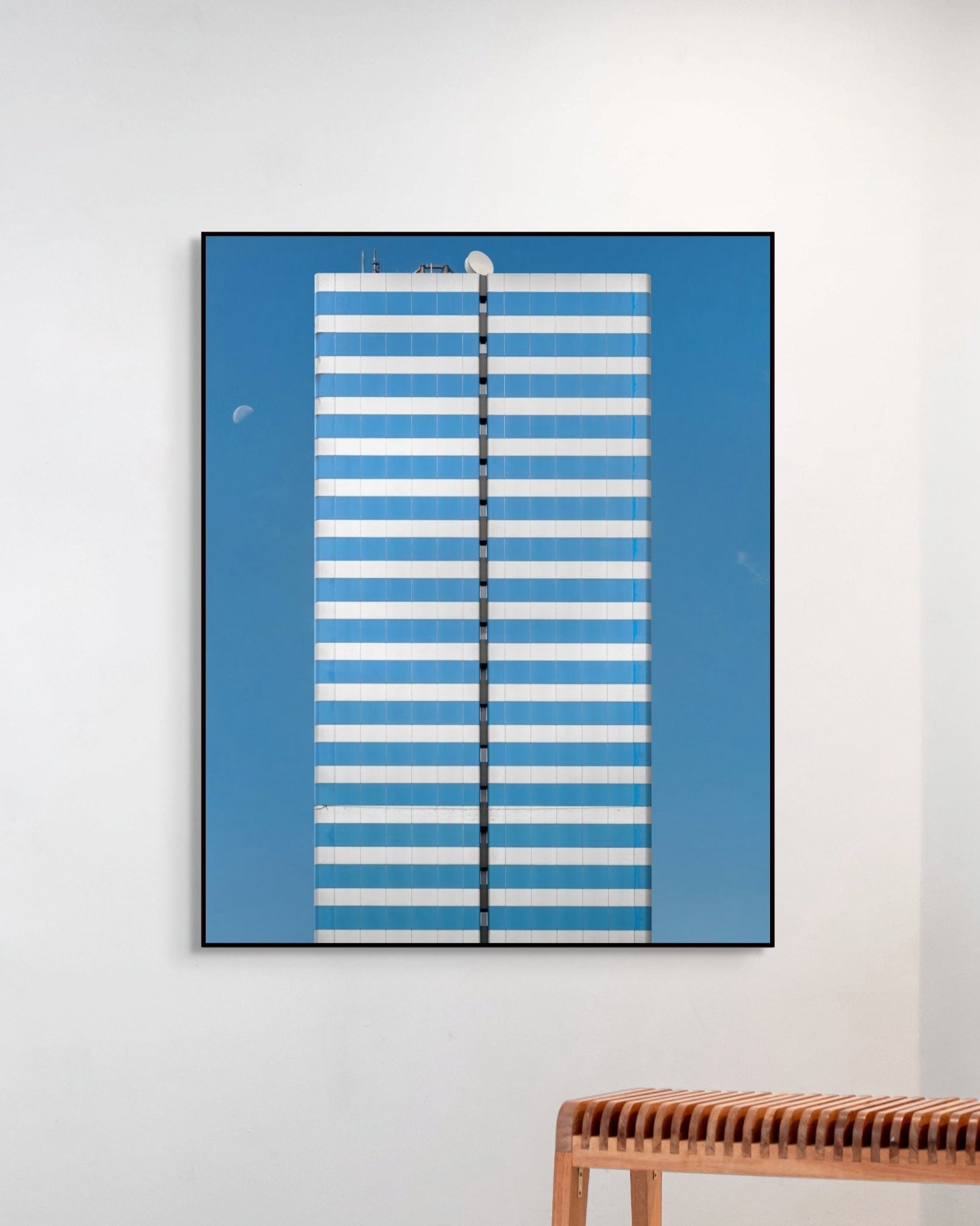 Framed abstract artwork with blue and white stripes on a light gray wall.