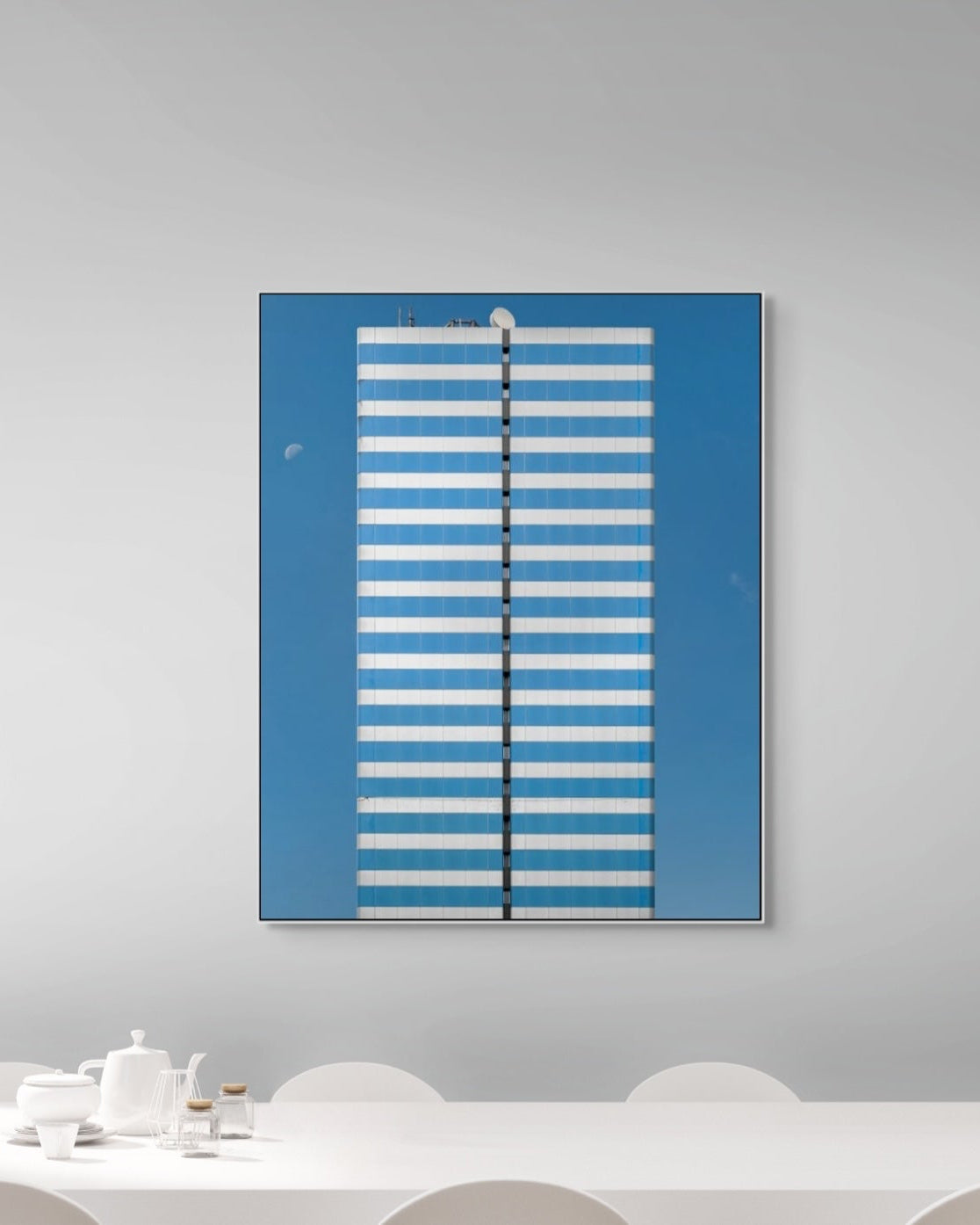 Blue and white striped wall art on a gray wall above a white table.